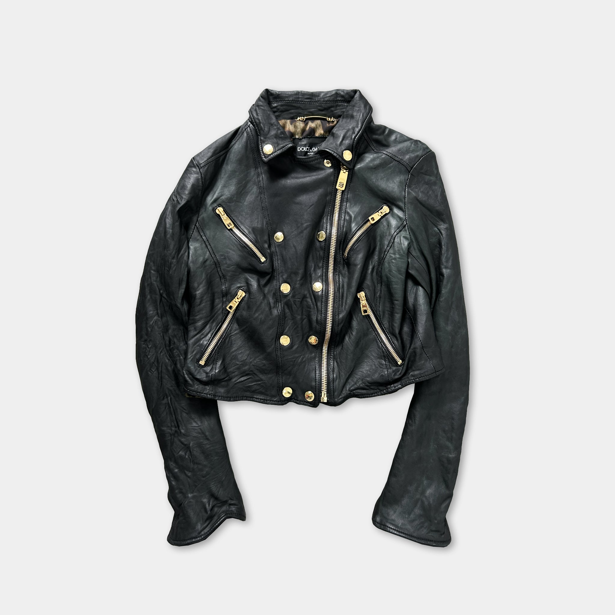 A black leather jacket with gold zippers and buttons, displayed against a white background.