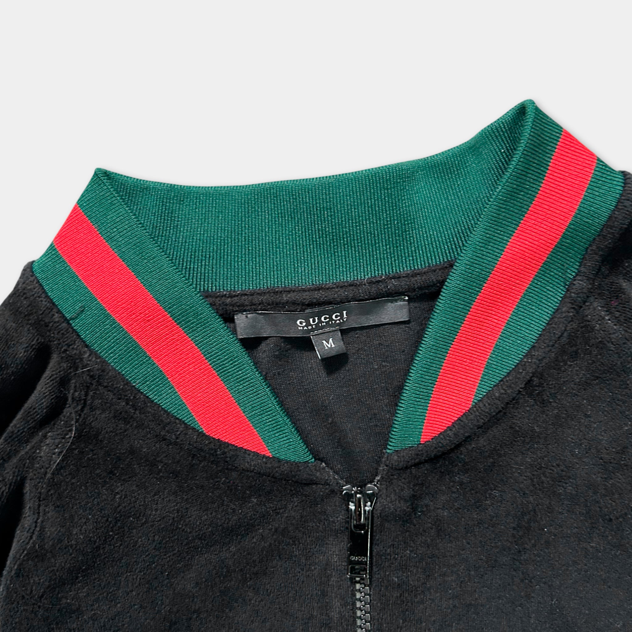 A close-up view of a black Gucci jacket with a green and red striped collar.