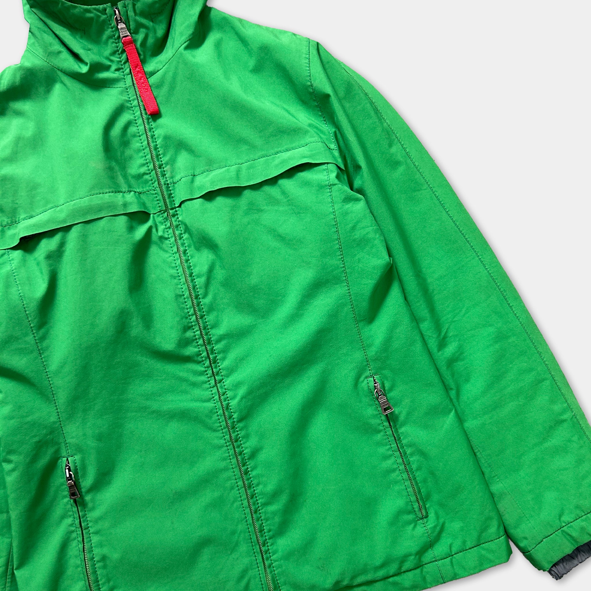 A bright green jacket with a zipper and pockets, displayed against a white background.