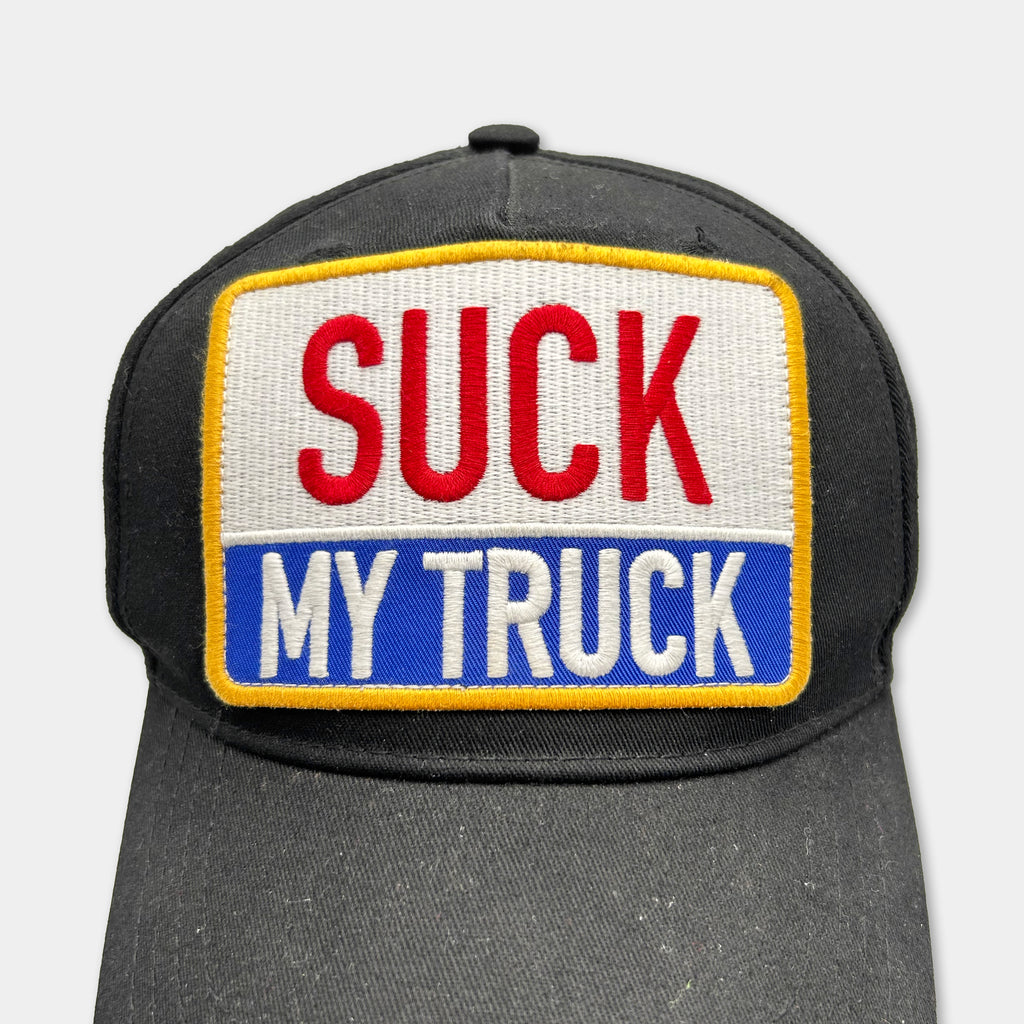 A black baseball cap with a patch on the front that says "SUCK MY TRUCK".