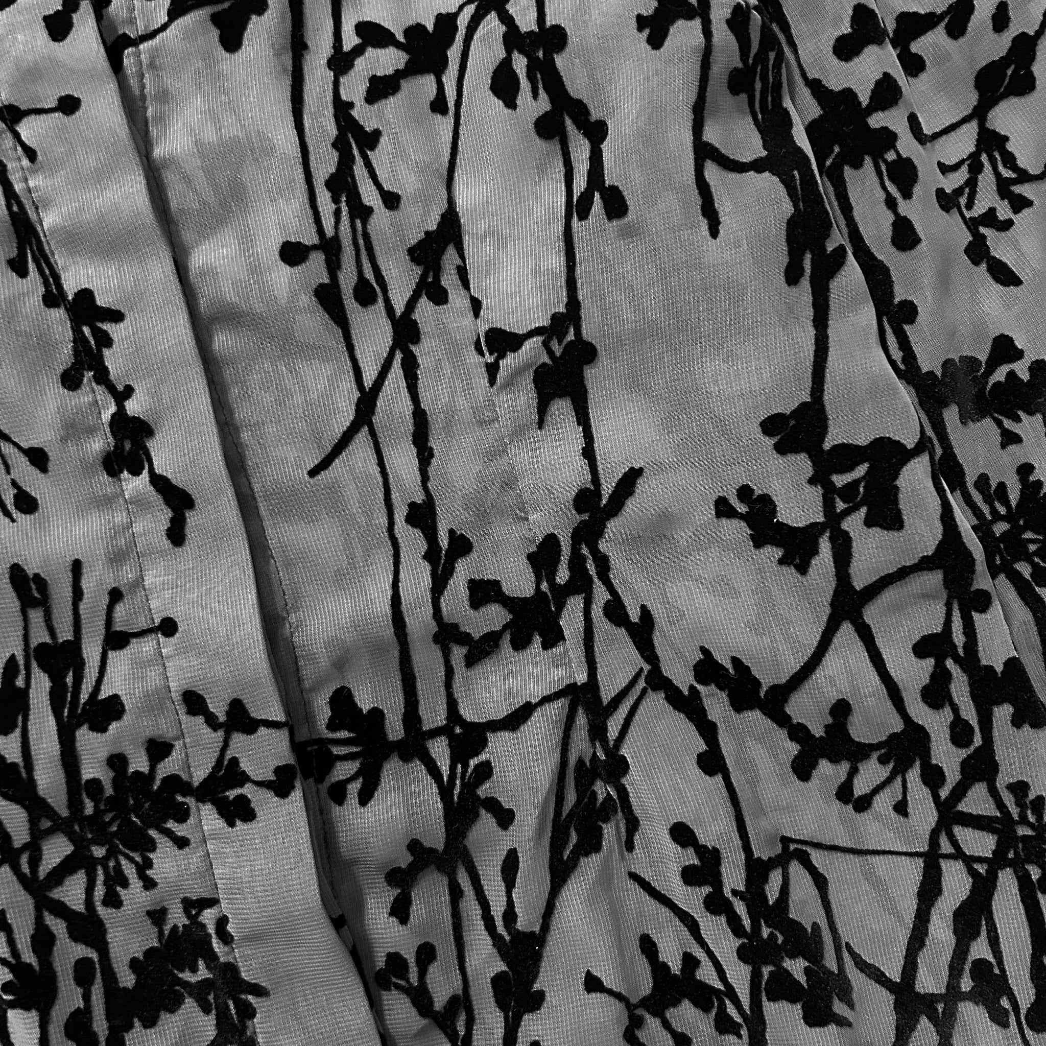 The image is a close-up of a fabric with a black and white floral pattern.