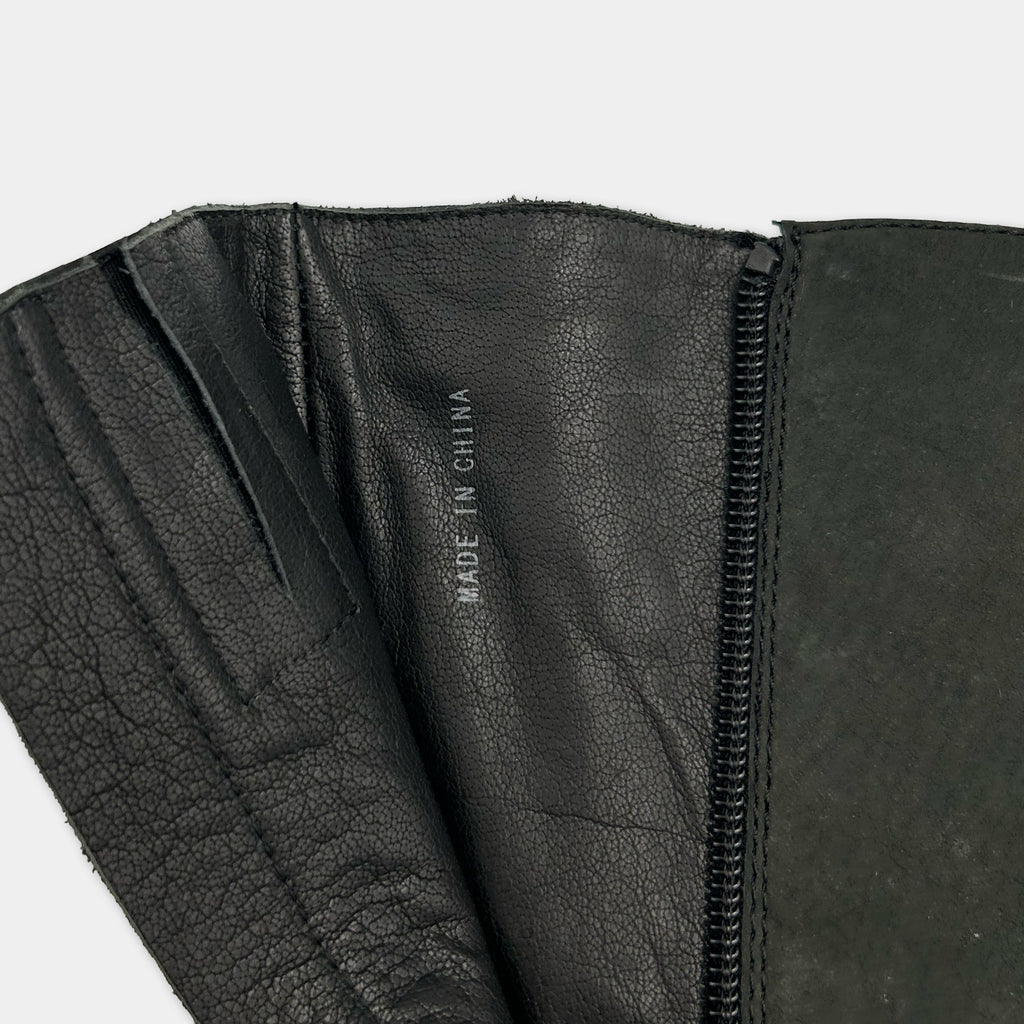 a close-up view of a black leather boot, with the label "MADE IN CHINA" printed on the inside of the boot.