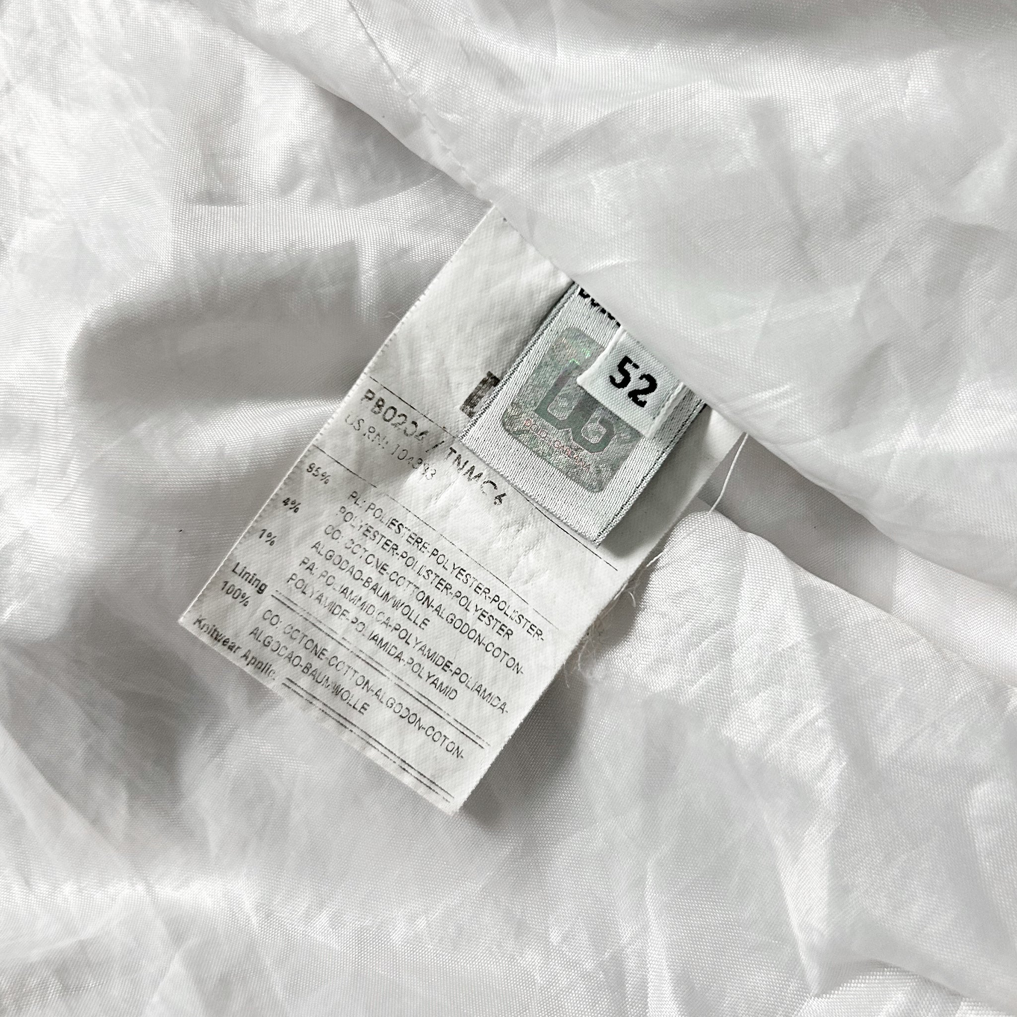 a close-up view of a white fabric, possibly a piece of clothing, with a small label attached to it. The label appears to contain text and a number, but the specific details are not clearly visible.