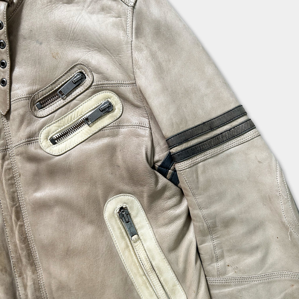 A close-up view of a tan leather jacket with multiple zippers and pockets.