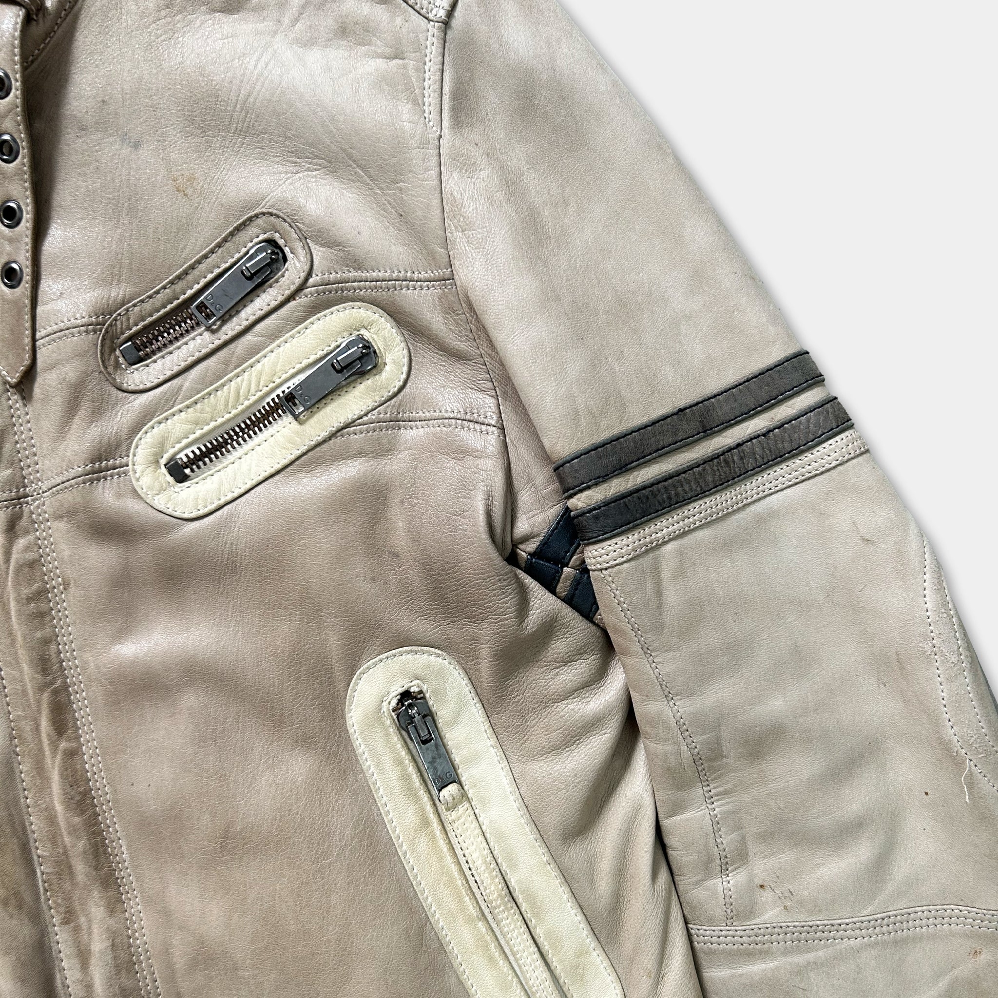 A close-up view of a tan leather jacket with multiple zippers and pockets.