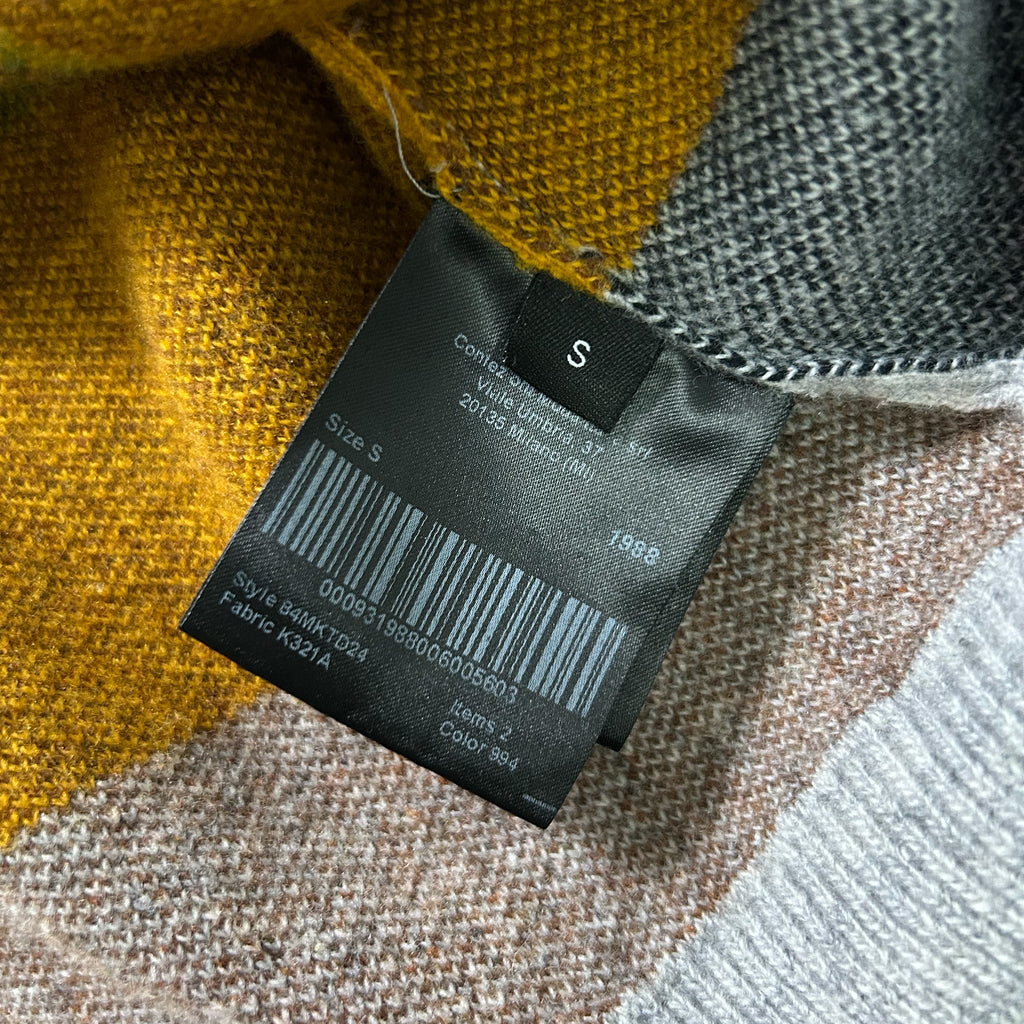 a close-up view of a fabric label attached to a piece of clothing, with a background of a multicolored fabric.