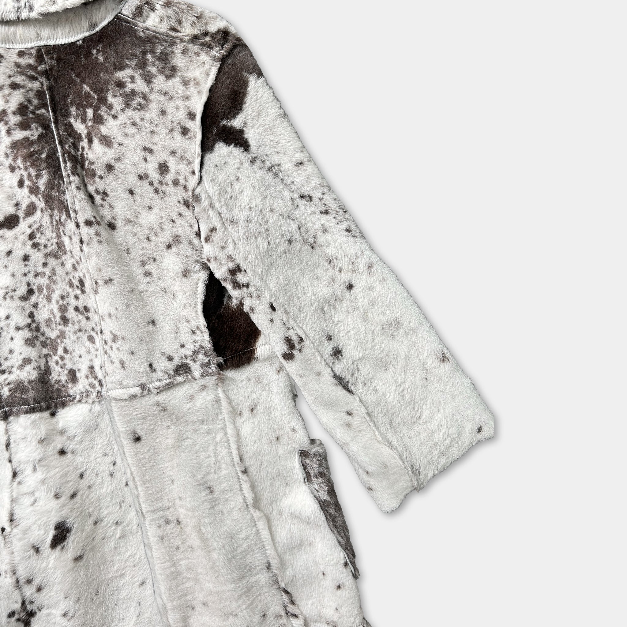 A close-up view of a long-sleeved jacket with a distinctive spotted pattern, likely made of fur or a similar material.