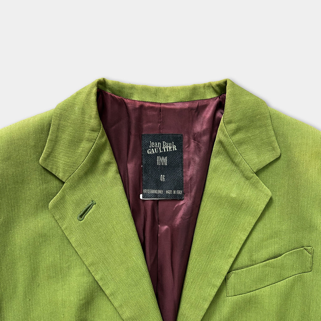A close-up view of a bright green blazer with a dark purple lining, featuring a label on the collar.