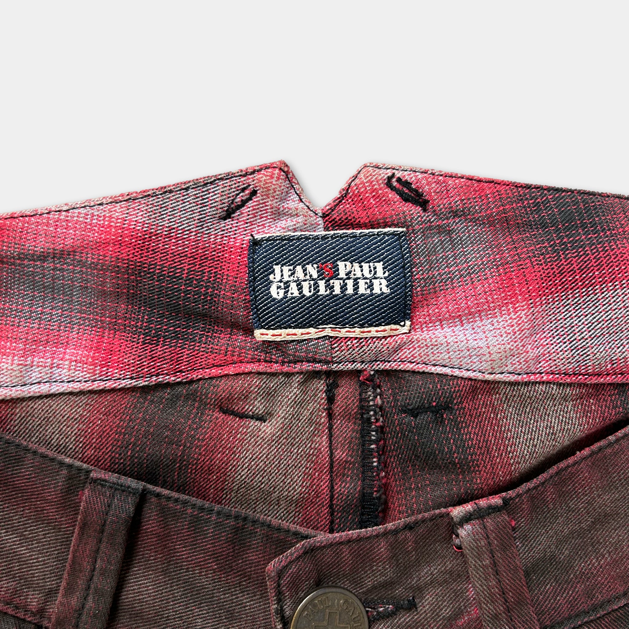 A close-up view of a pair of plaid pants with a label that reads "Jean Paul Gaultier".