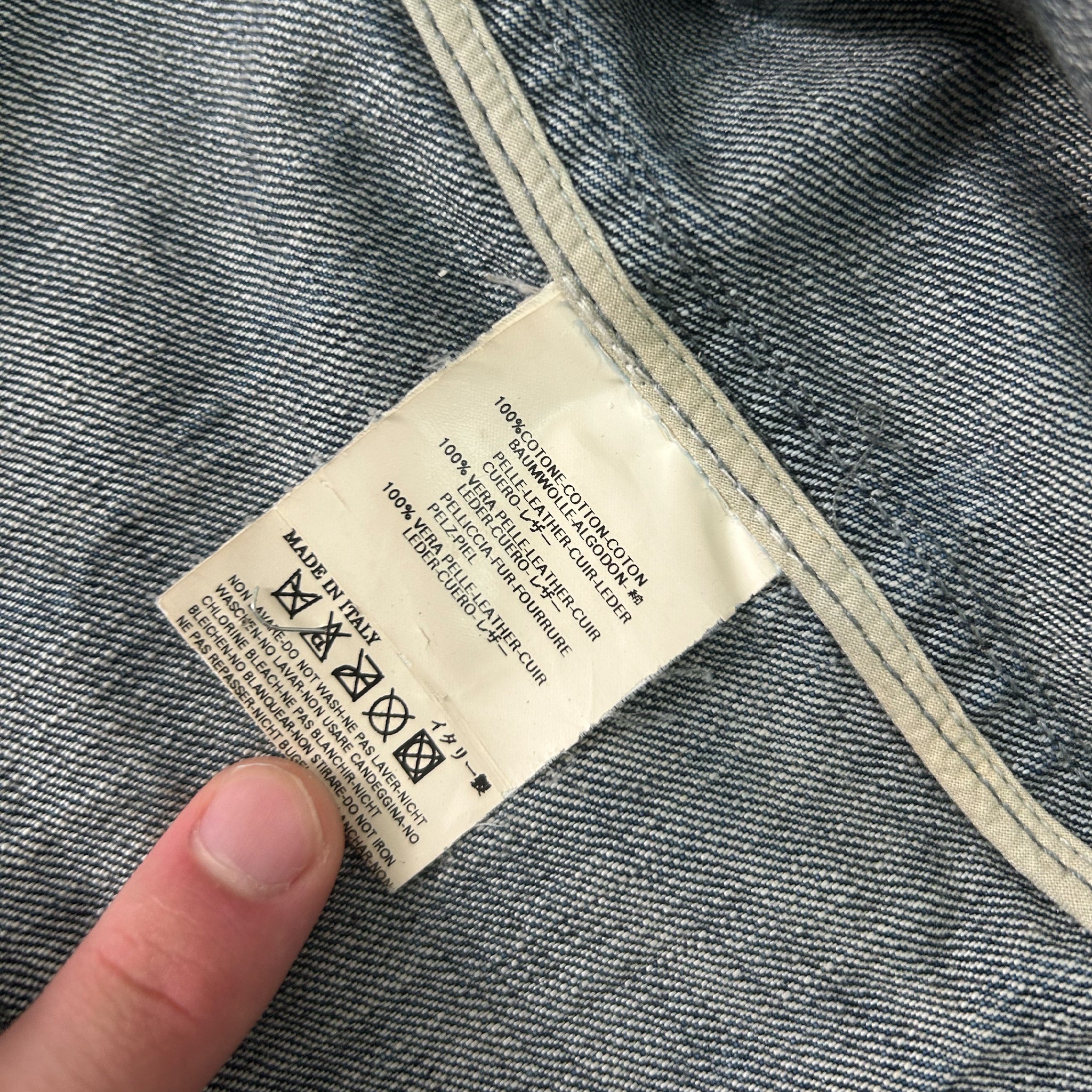 A close-up view of a denim fabric, with a label attached to it. The label appears to contain text and symbols related to the care and maintenance of the fabric.
