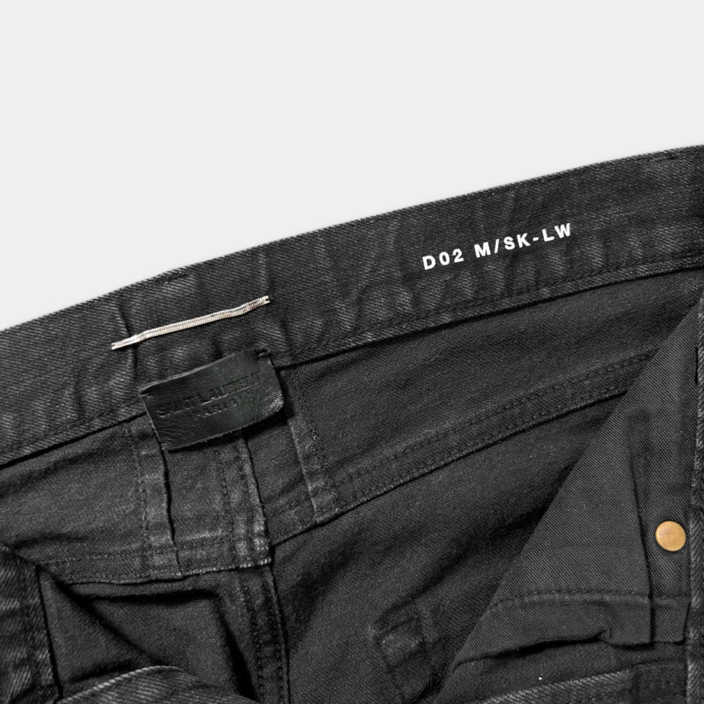 a close-up view of a pair of black jeans, with a label on the waistband and a zipper visible.