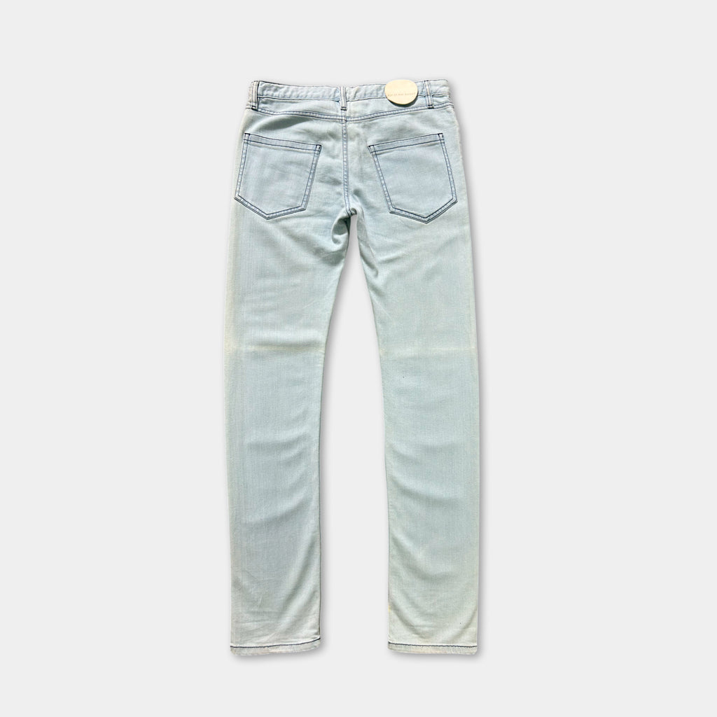 A pair of light blue denim jeans with a small white tag on the back pocket.