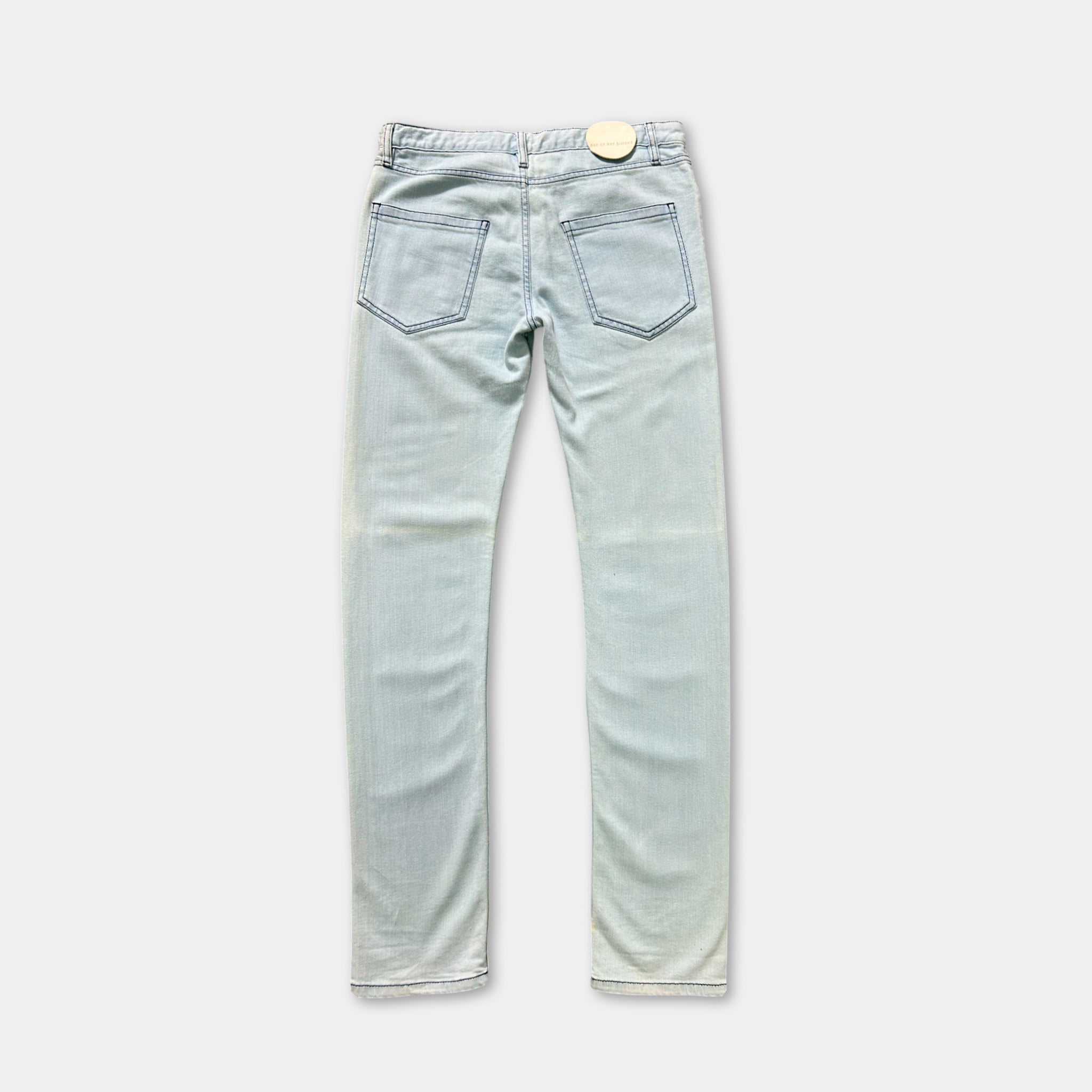 A pair of light blue denim jeans with a small white tag on the back pocket.