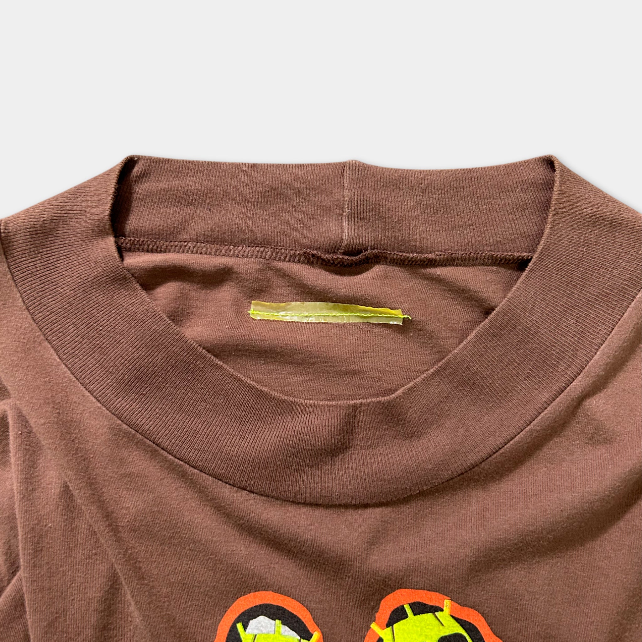 a brown t-shirt with a yellow label on the collar.