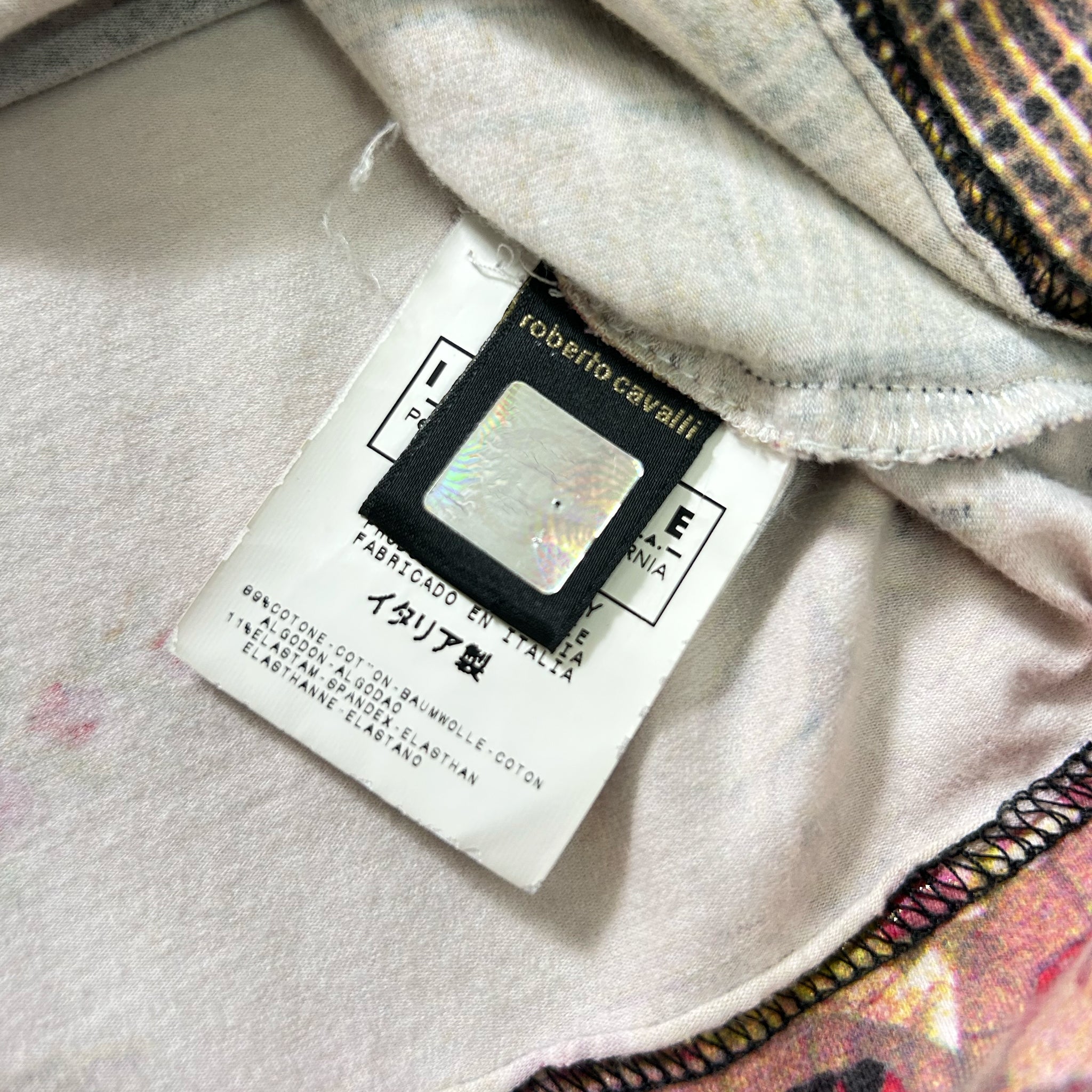 a close-up view of a fabric label with text and a small, reflective object attached to it.
