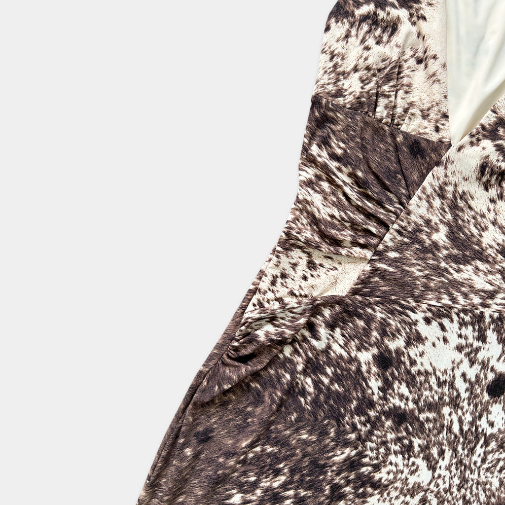 a close-up view of a patterned fabric, possibly a dress or garment, with a mix of brown and white colors and a textured appearance.