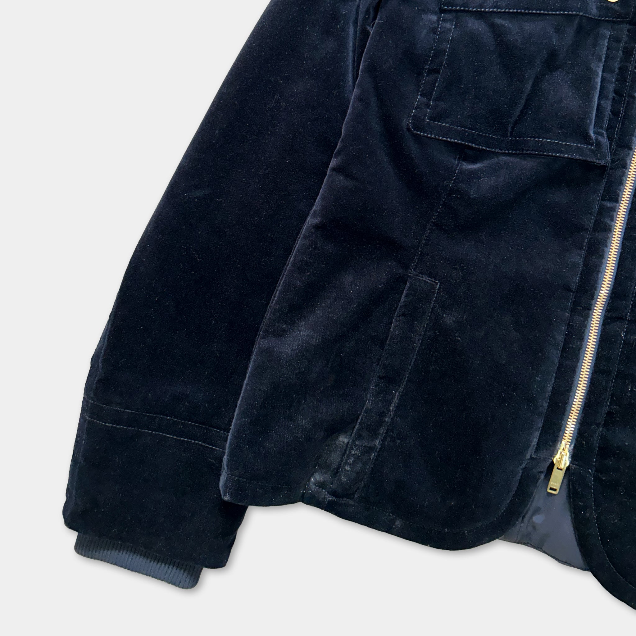 A close-up view of a dark blue velvet jacket with a zipper and pockets.