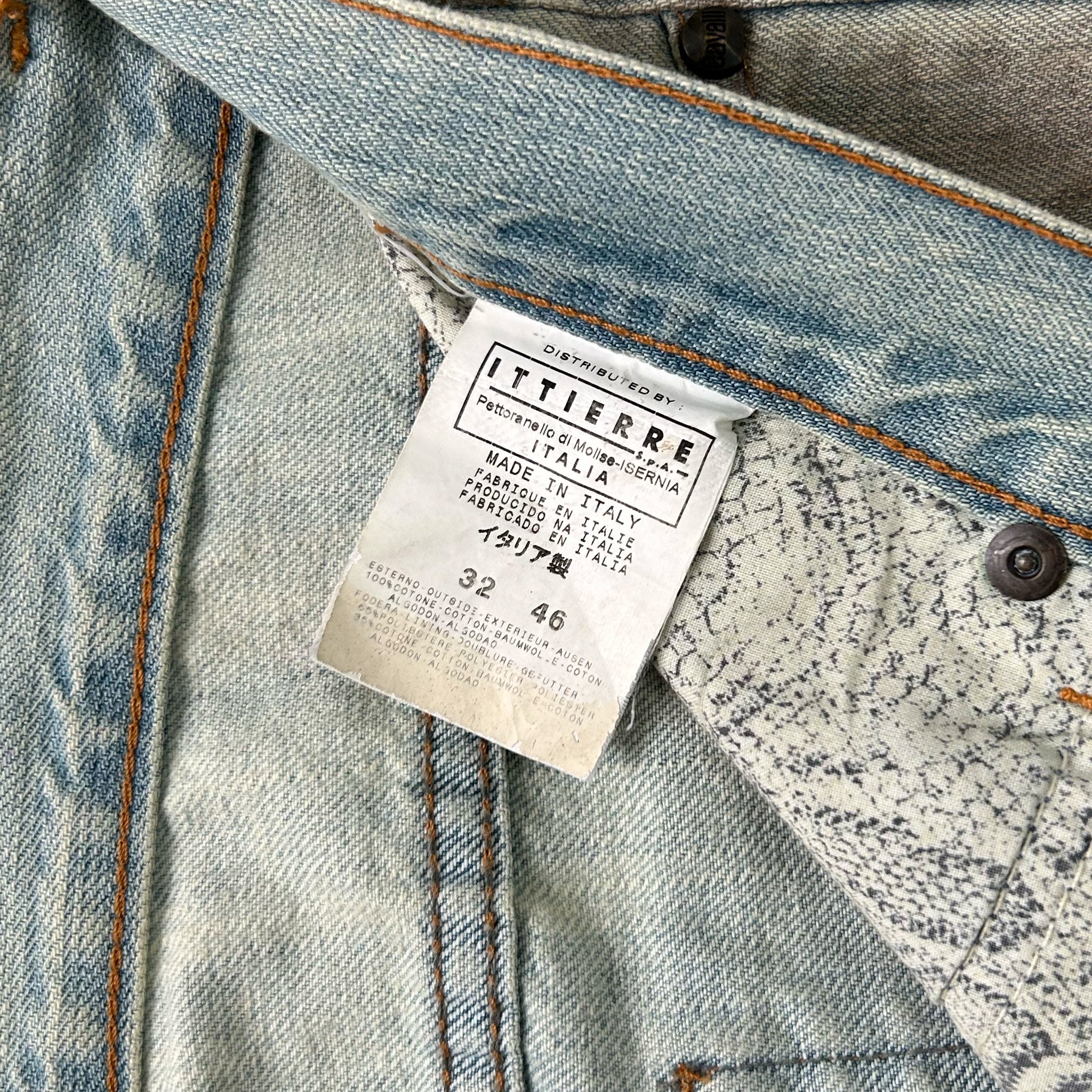 a close-up view of a denim fabric, possibly a pair of jeans, with a label attached to it. The label appears to be a label from a clothing brand, and it contains information about the product.