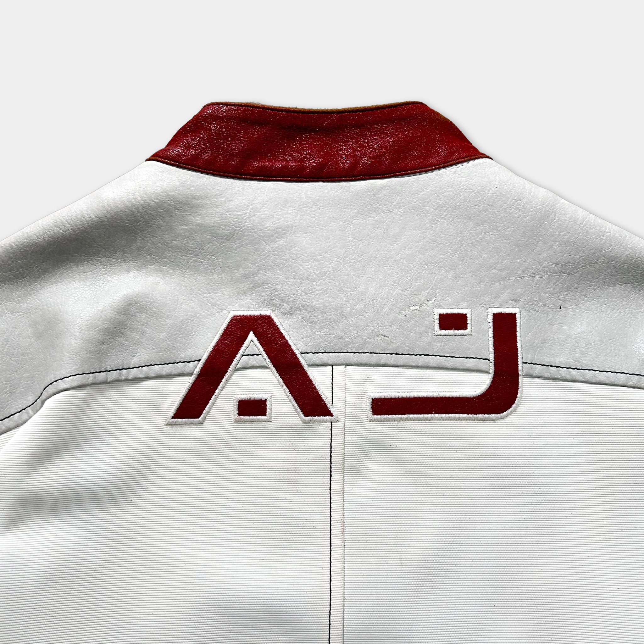 a close-up view of a white jacket with a red collar and a red logo on the back.