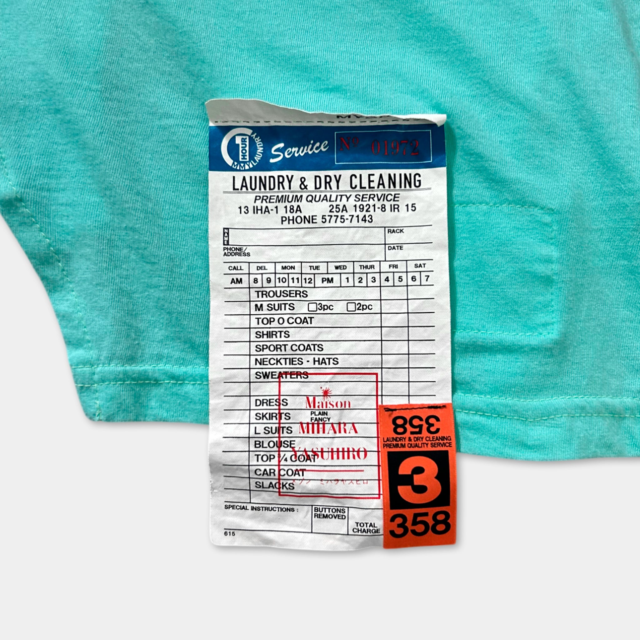 A laundry and dry cleaning receipt with a price tag attached to a turquoise fabric.