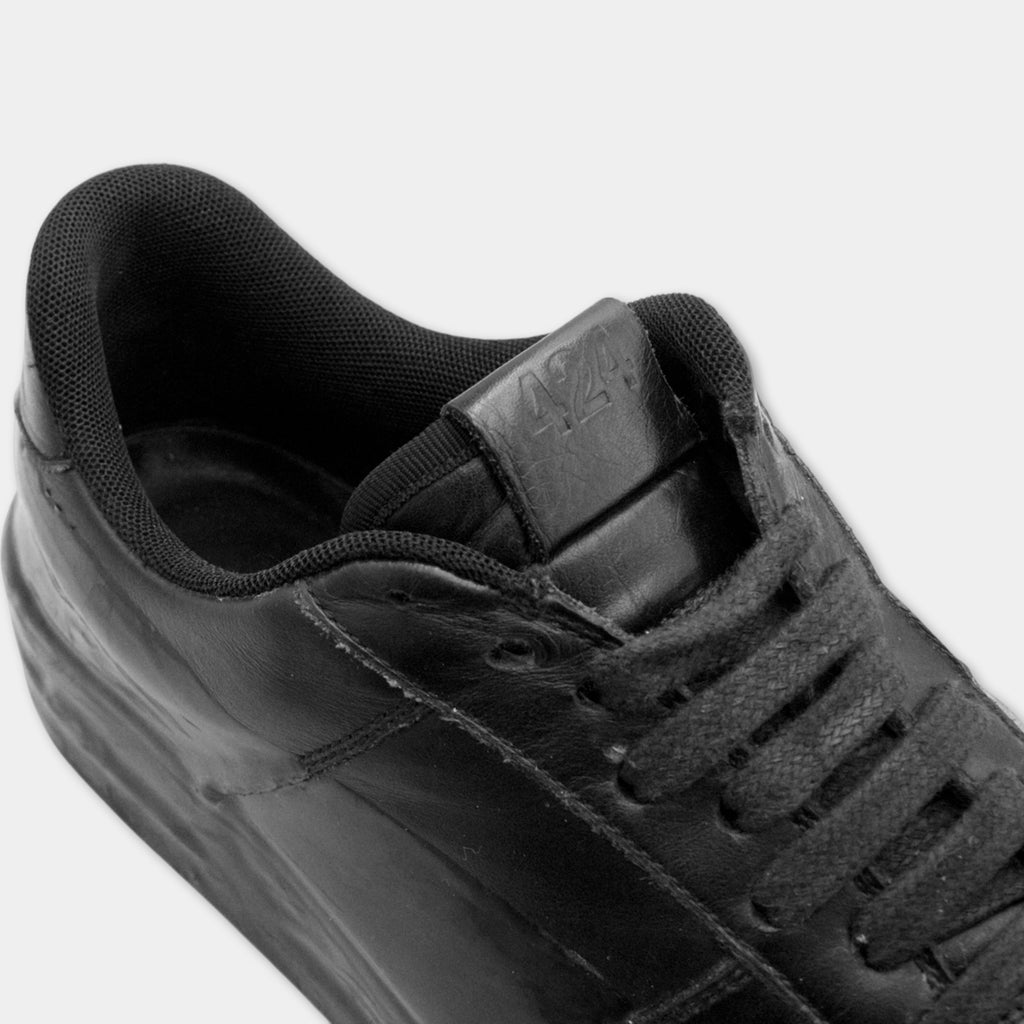 A close-up view of a black leather sneaker with a lace-up design.