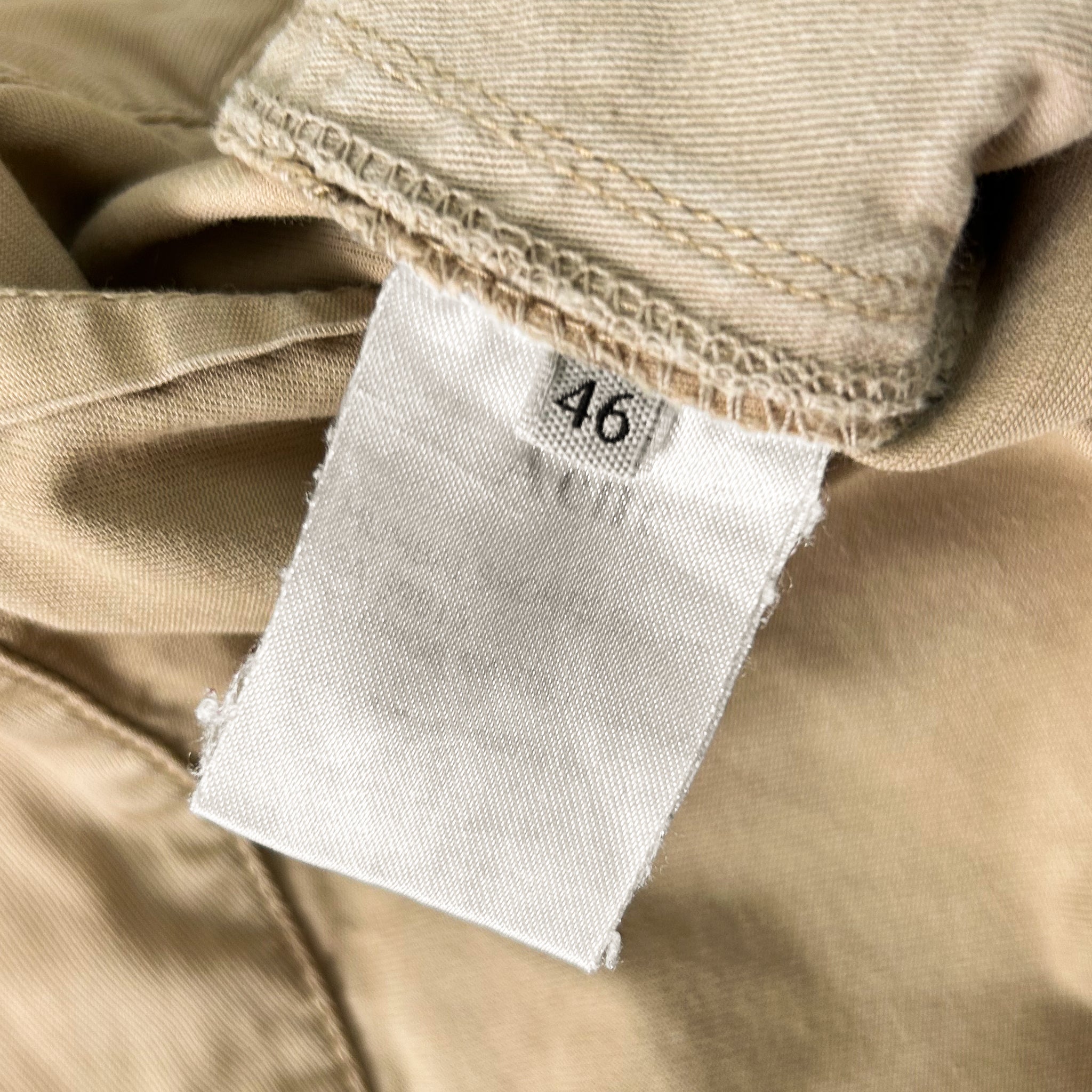 A close-up view of a white label with the number 46 printed on it, attached to a beige fabric.