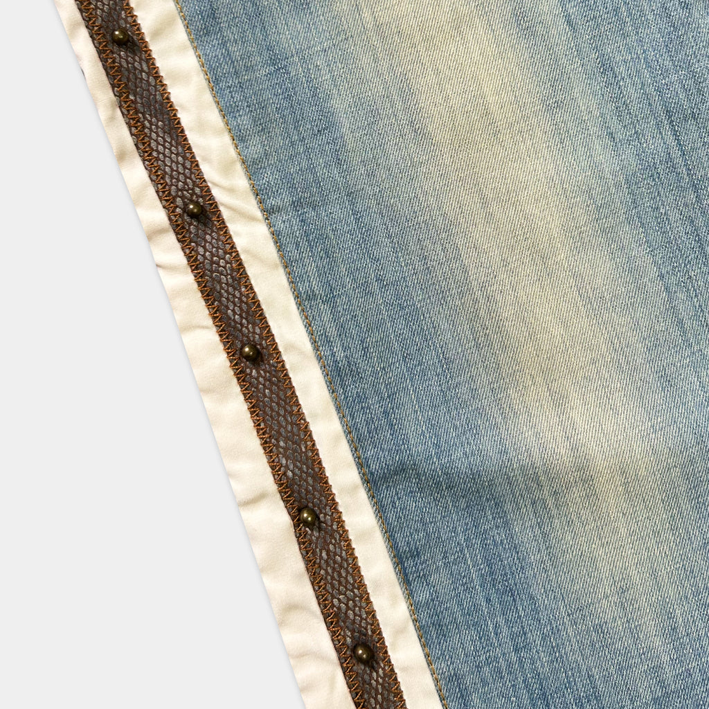 a close-up view of a piece of blue denim fabric with a decorative metal trim.