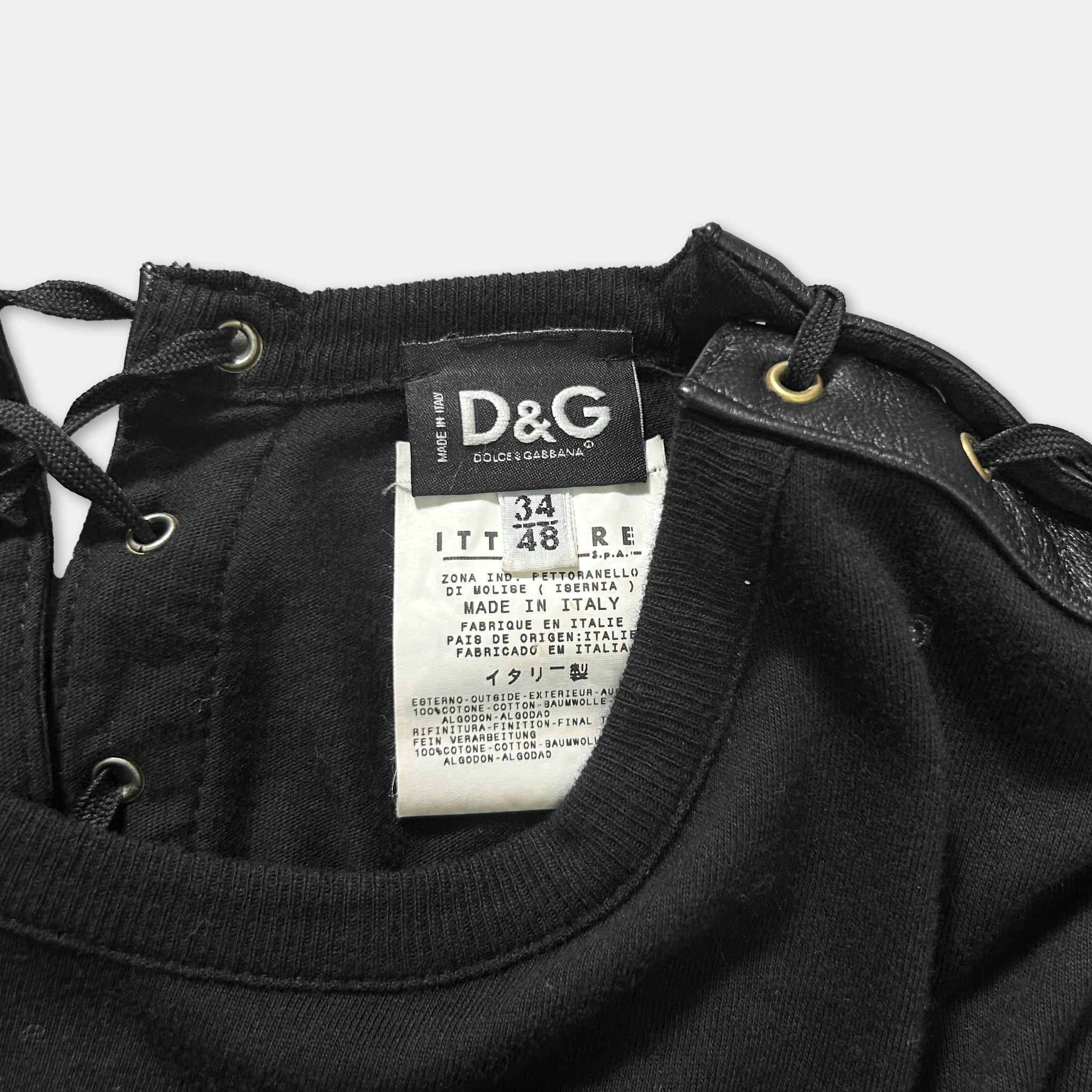 a close-up view of a black garment, possibly a shirt or blouse, with a label attached to it. The label appears to be from a brand like D&G, indicating that it is a product of Italy.