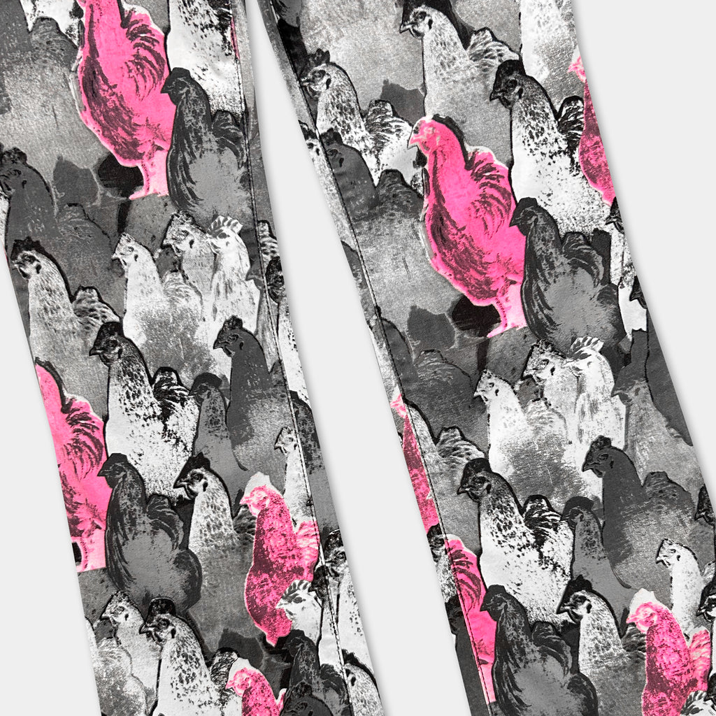 a pair of pants with a repeating pattern of black and white silhouettes of chickens, with some of the chickens being pink.