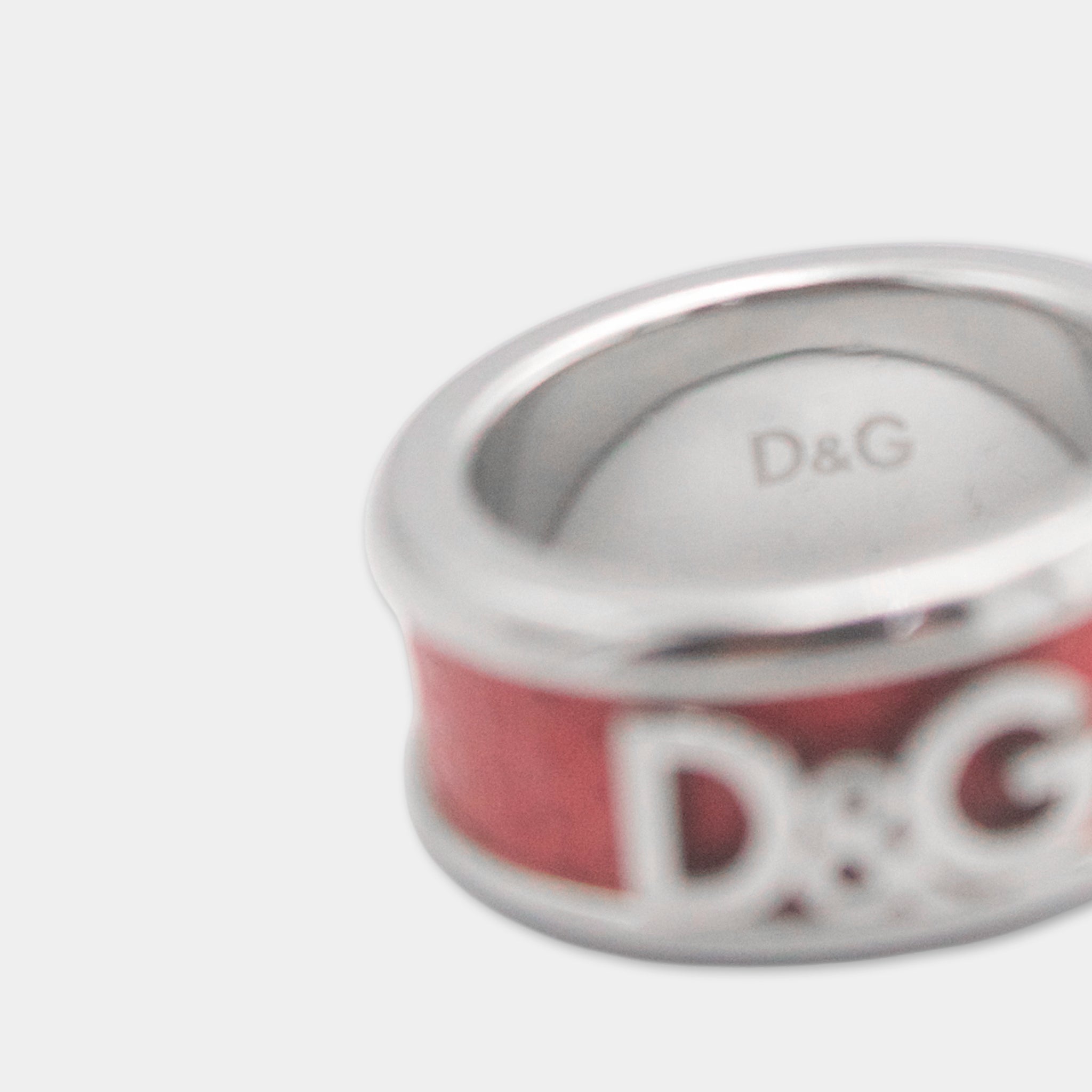 A close-up of a silver ring with a red band and the letters "D&G" engraved on it.