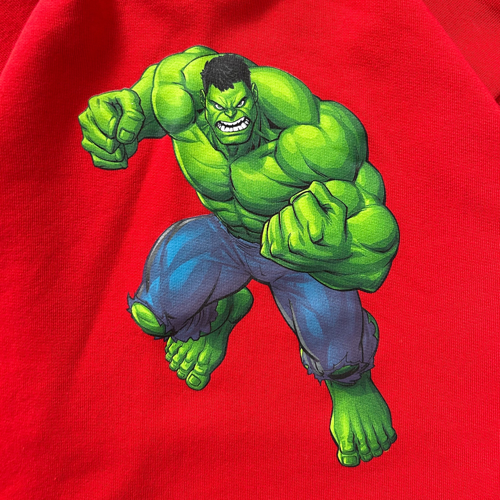A muscular, green-skinned character with a determined expression is depicted in a dynamic fighting stance against a red background.