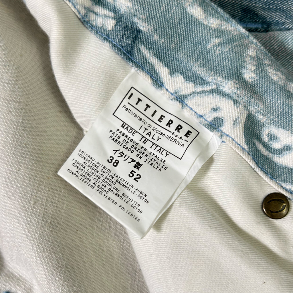 a close-up view of a label on a piece of clothing, likely a denim item, with a patterned fabric visible in the background.