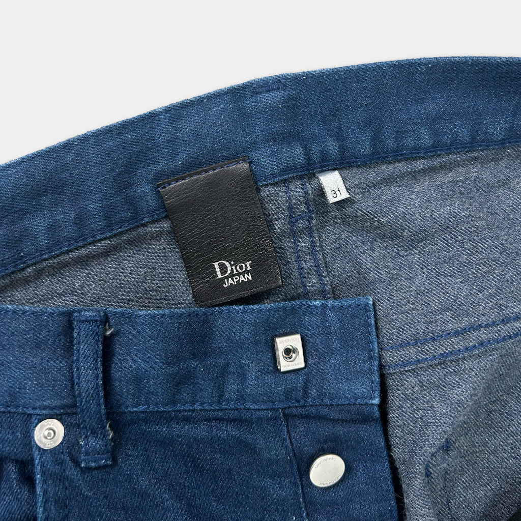 A close-up view of a pair of blue denim jeans, with a black label attached to the waistband.