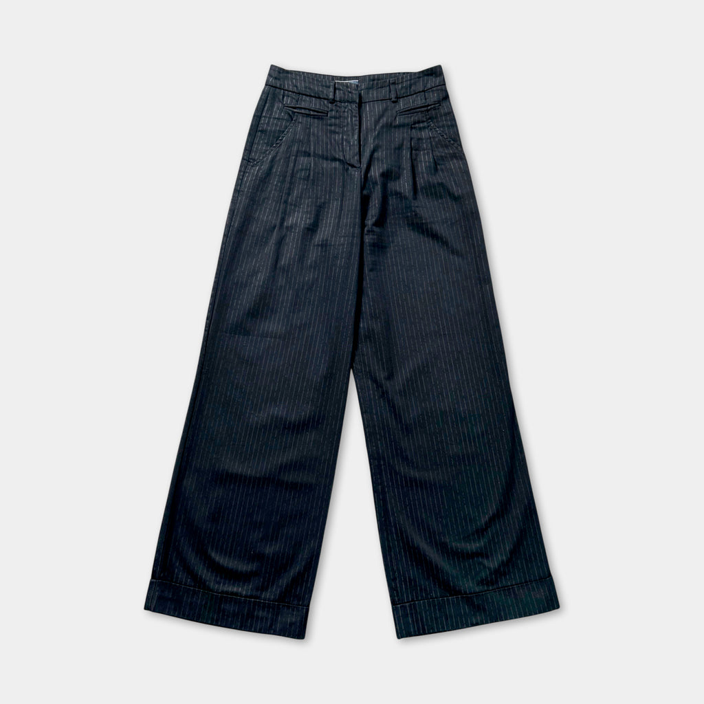 A pair of black pinstriped wide-leg pants against a white background.