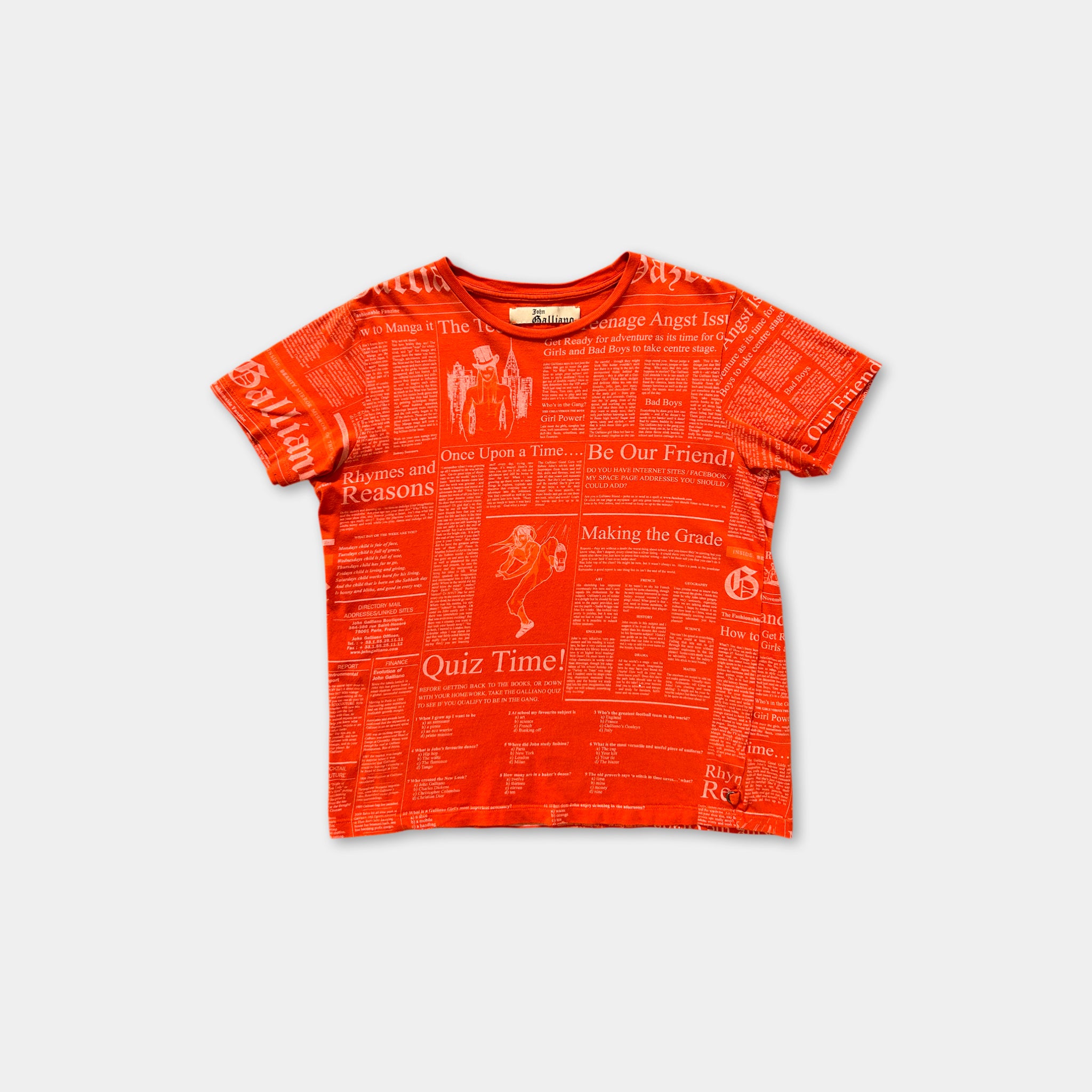 The image is a red t-shirt with a repeating pattern of newspaper-style text and images, including phrases such as "Quiz Time!" and "Making the Grade".