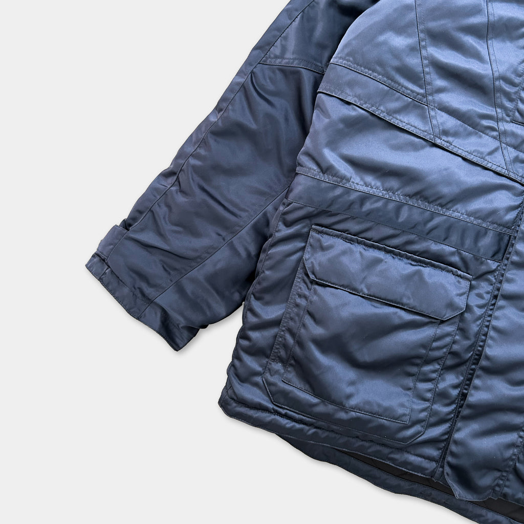A close-up view of a dark blue, padded jacket with multiple pockets and sleeves.