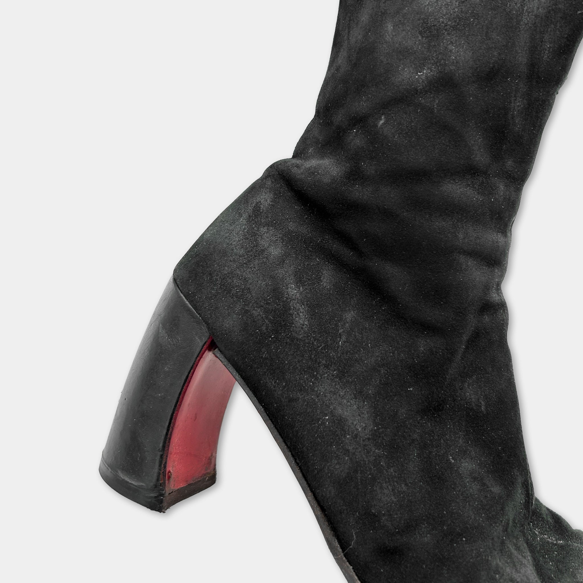 A close-up view of a black suede boot with a red heel.