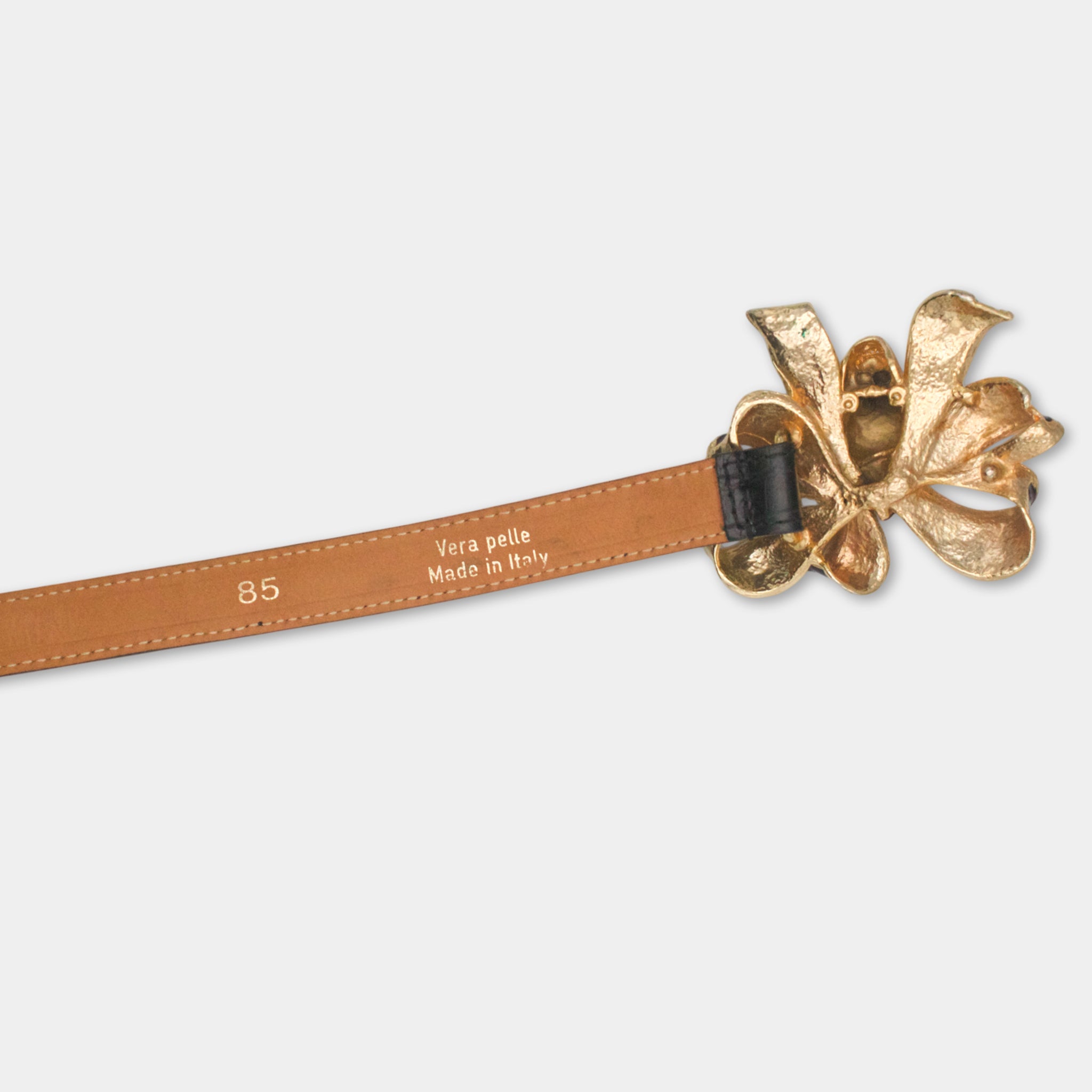 A brown leather belt with a decorative metal flower buckle.