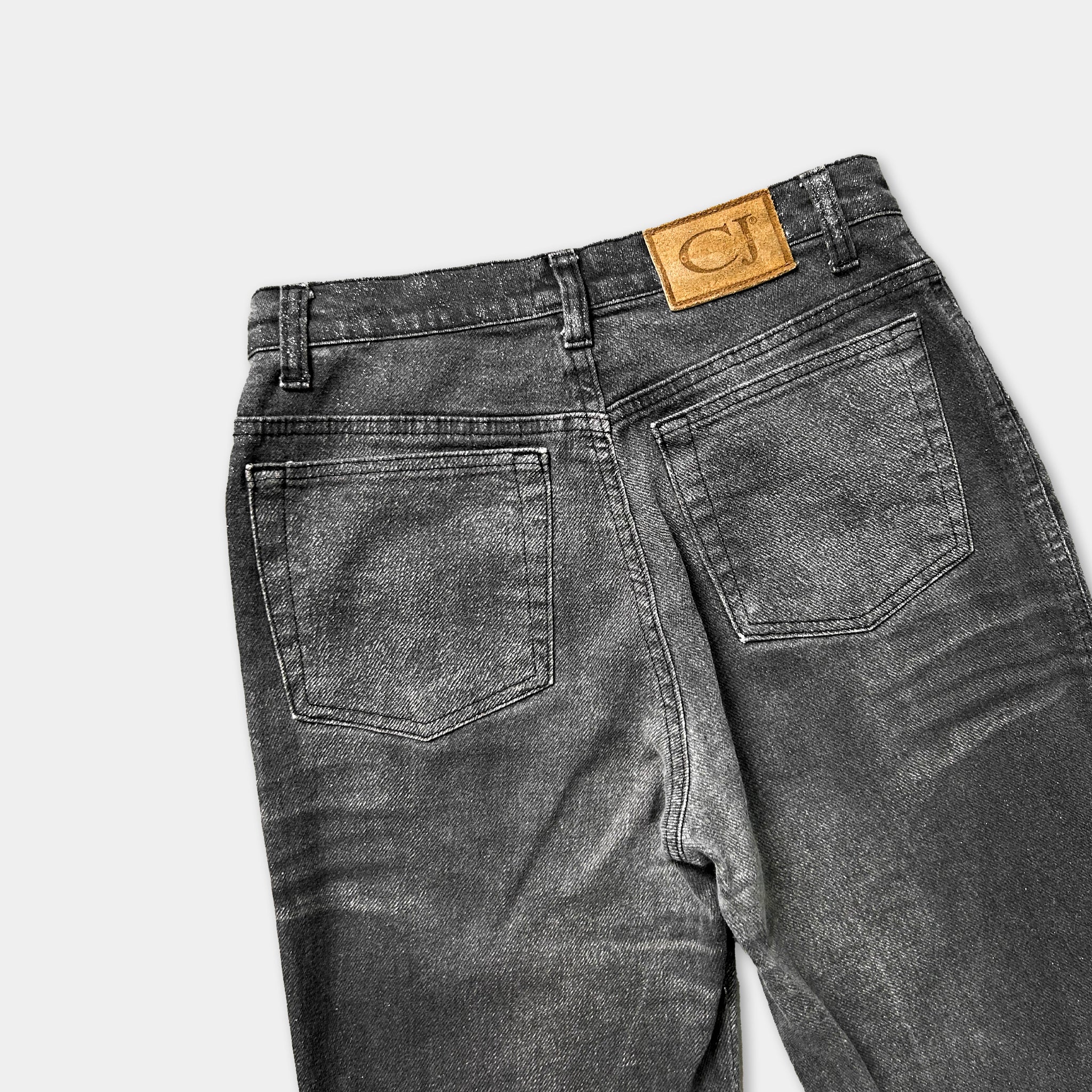 A pair of black jeans with a tan leather patch on the back pocket.
