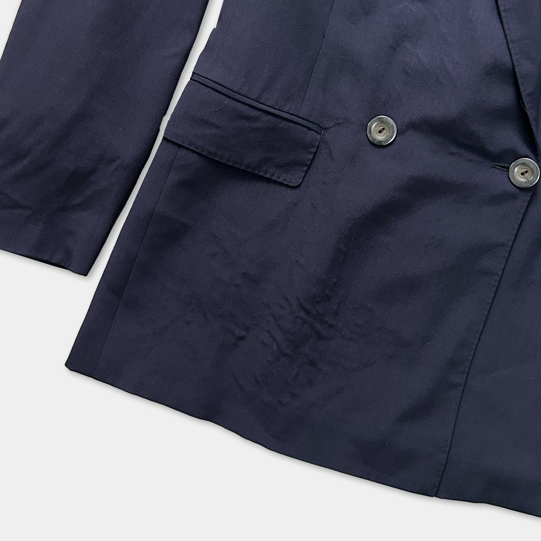 A close-up view of a navy blue blazer with a buttoned front and a pocket.