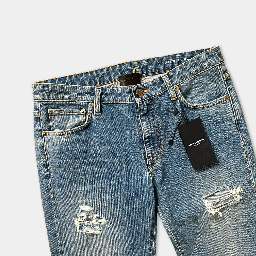 A pair of blue jeans with a black tag attached to the waistband.