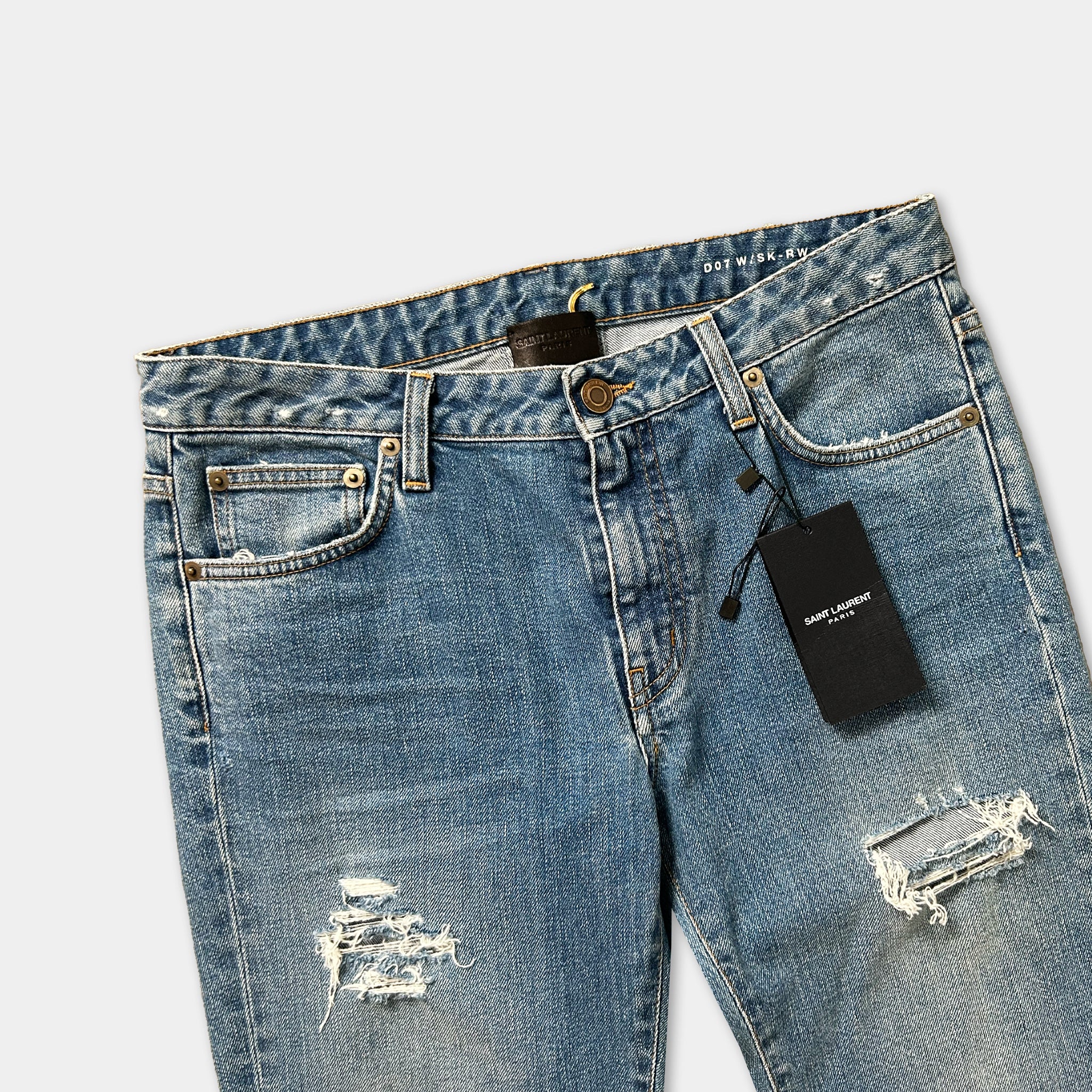 A pair of blue jeans with a black tag attached to the waistband.