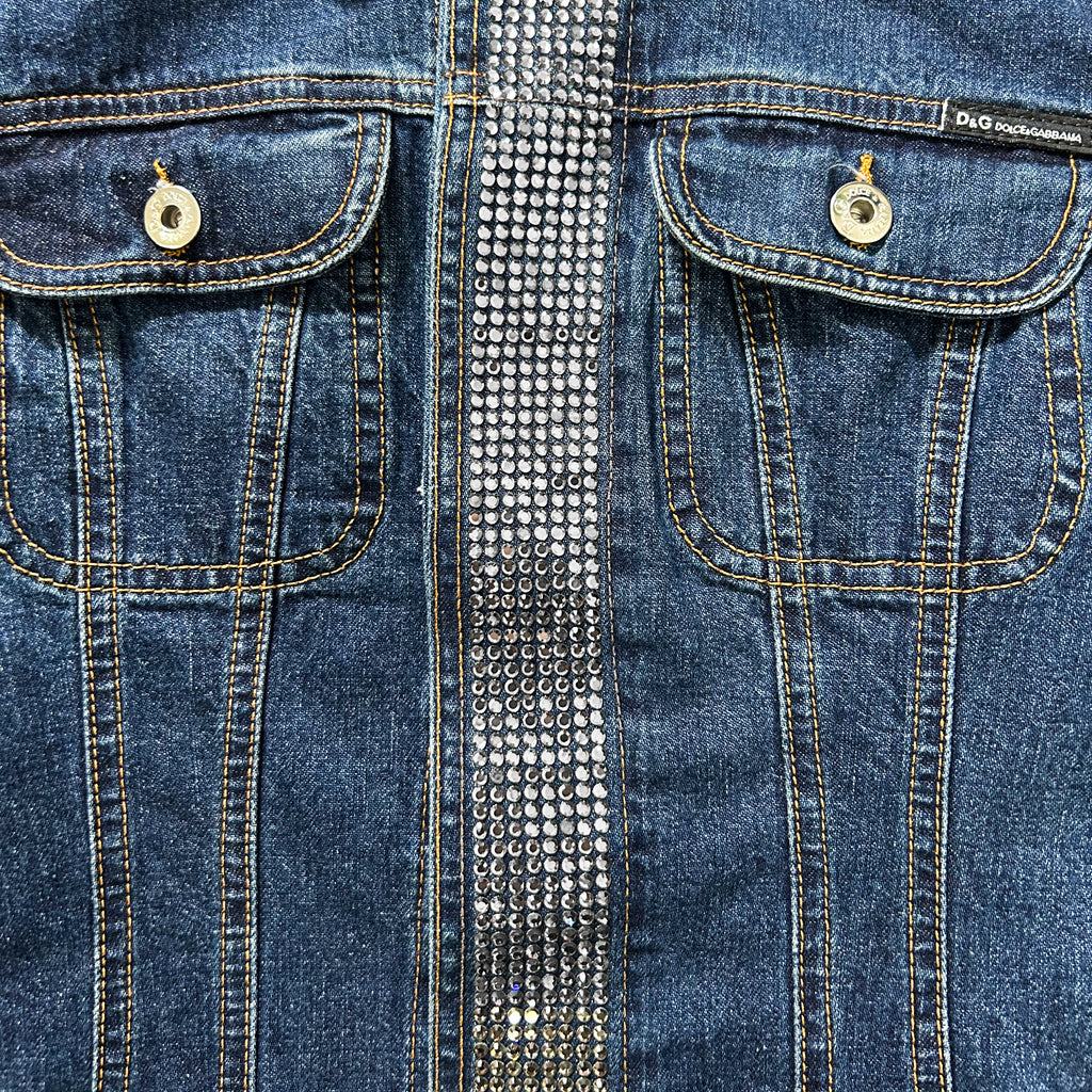 a close-up view of a pair of blue denim jeans with a silver rhinestone embellishment running down the center of the pocket.