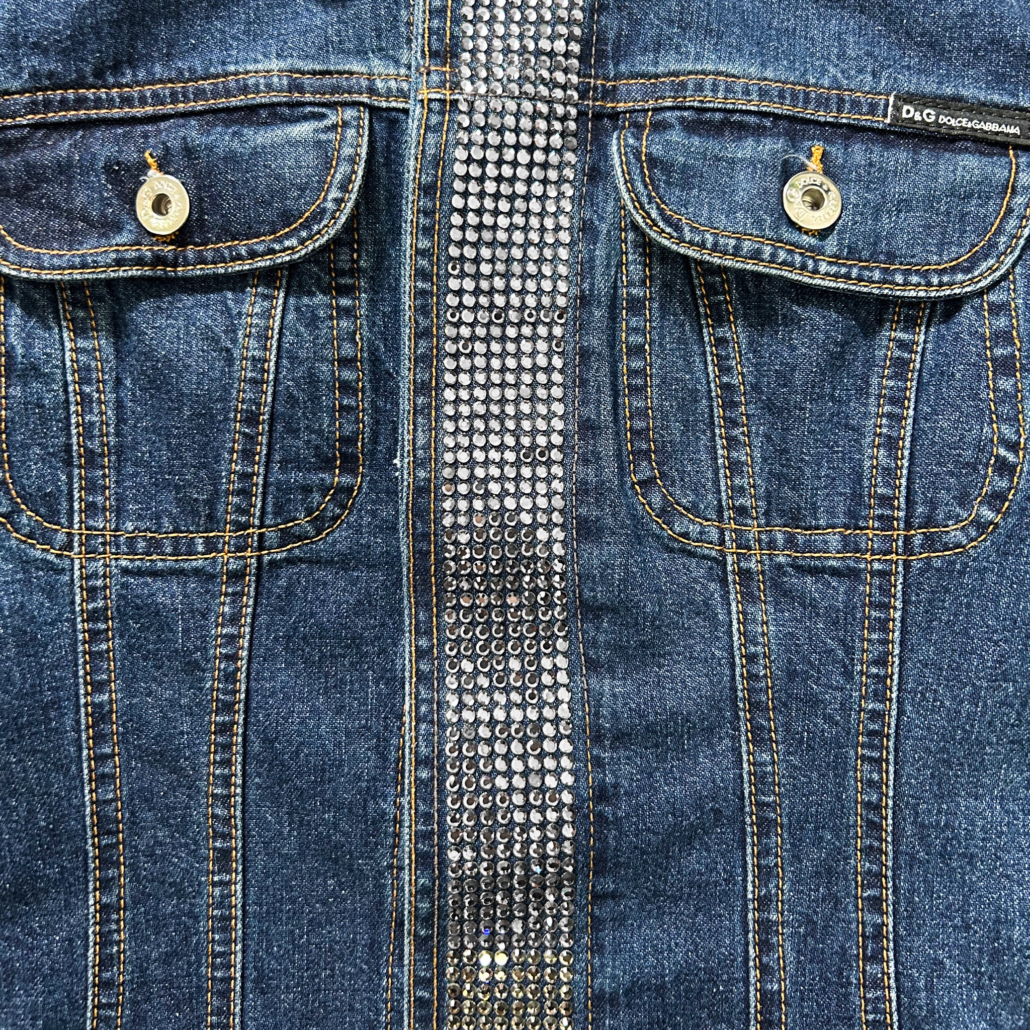a close-up view of a pair of blue denim jeans with a silver rhinestone embellishment running down the center of the pocket.