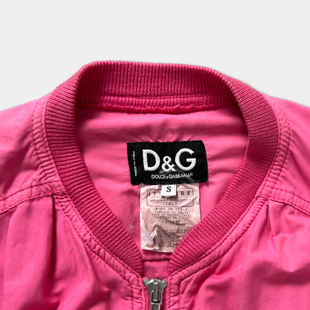 A close-up view of a bright pink jacket with a collar and zipper, featuring a label on the collar.