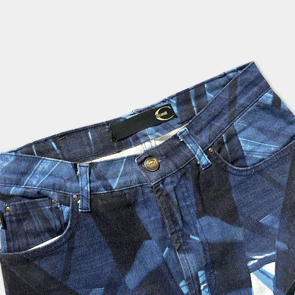 A pair of blue jeans with a geometric pattern, featuring a black button and a gold zipper pull.