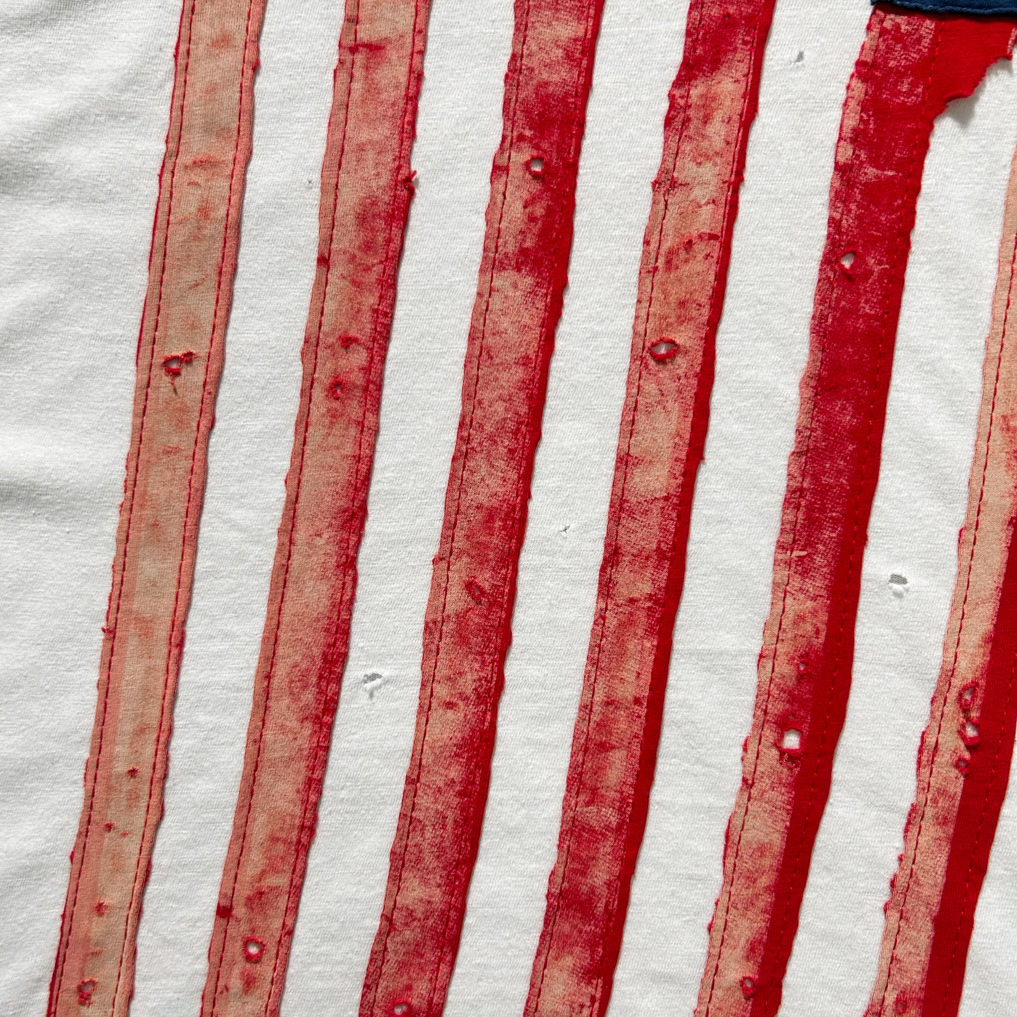 a close-up view of a fabric with red and white stripes, with some red paint or stain visible on the fabric.