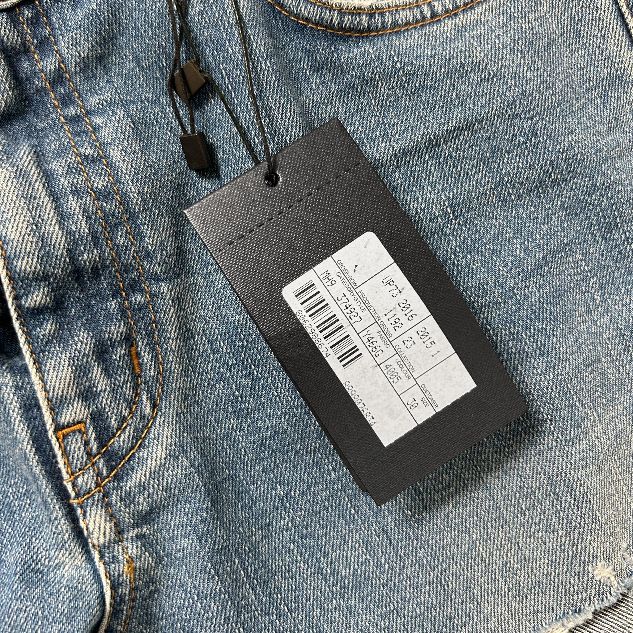 A black price tag attached to a pair of blue jeans.