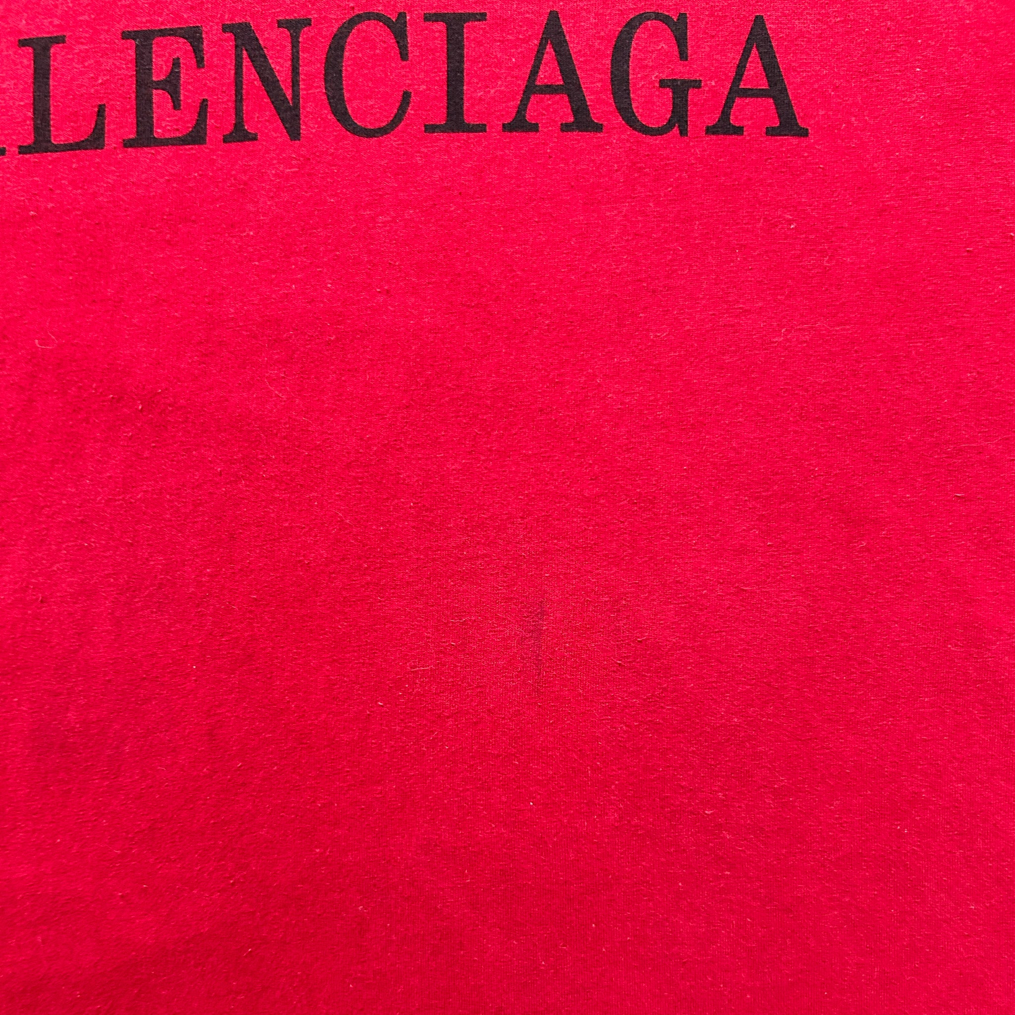The image is a close-up of a red fabric with the word "LENCIAGA" printed on it in black text.