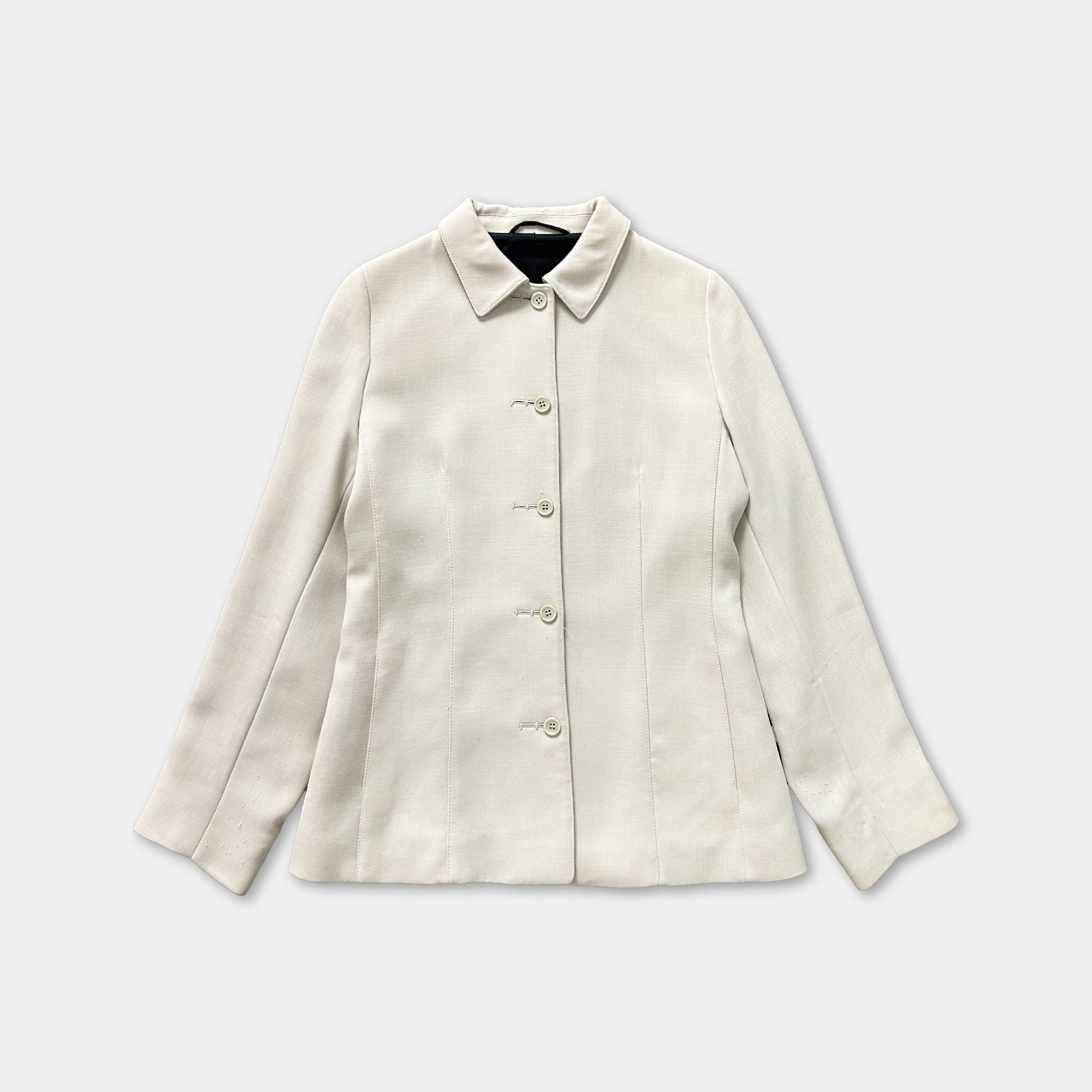A cream-colored blazer with a button-down front and long sleeves, displayed against a white background.